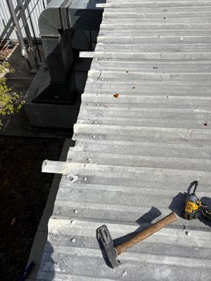 Metal roof panels with hammer and drill on surface