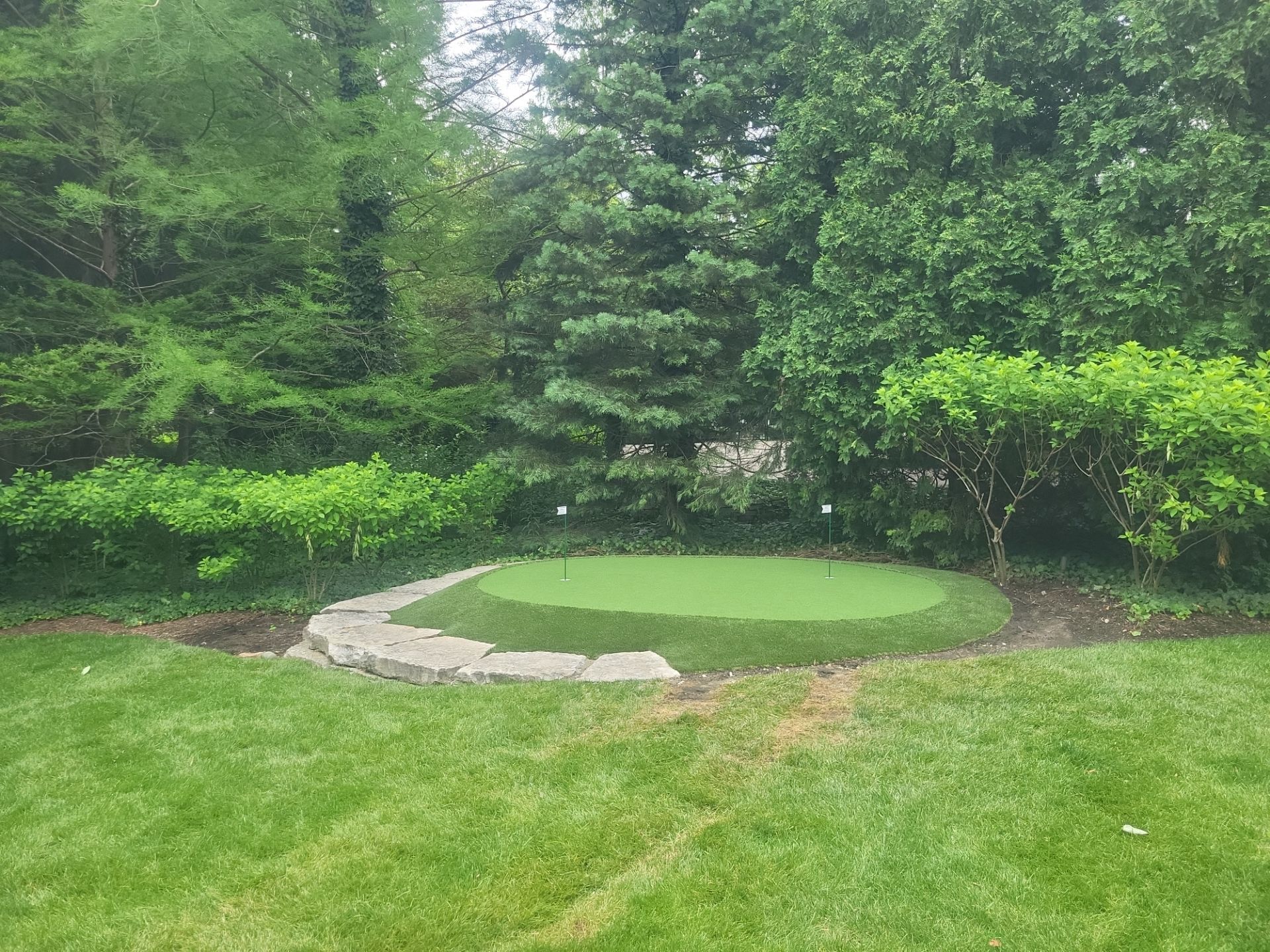 Small New Albany Synthetic Turf Putting Green with Natural Stone Border by Southwest Greens Midwest