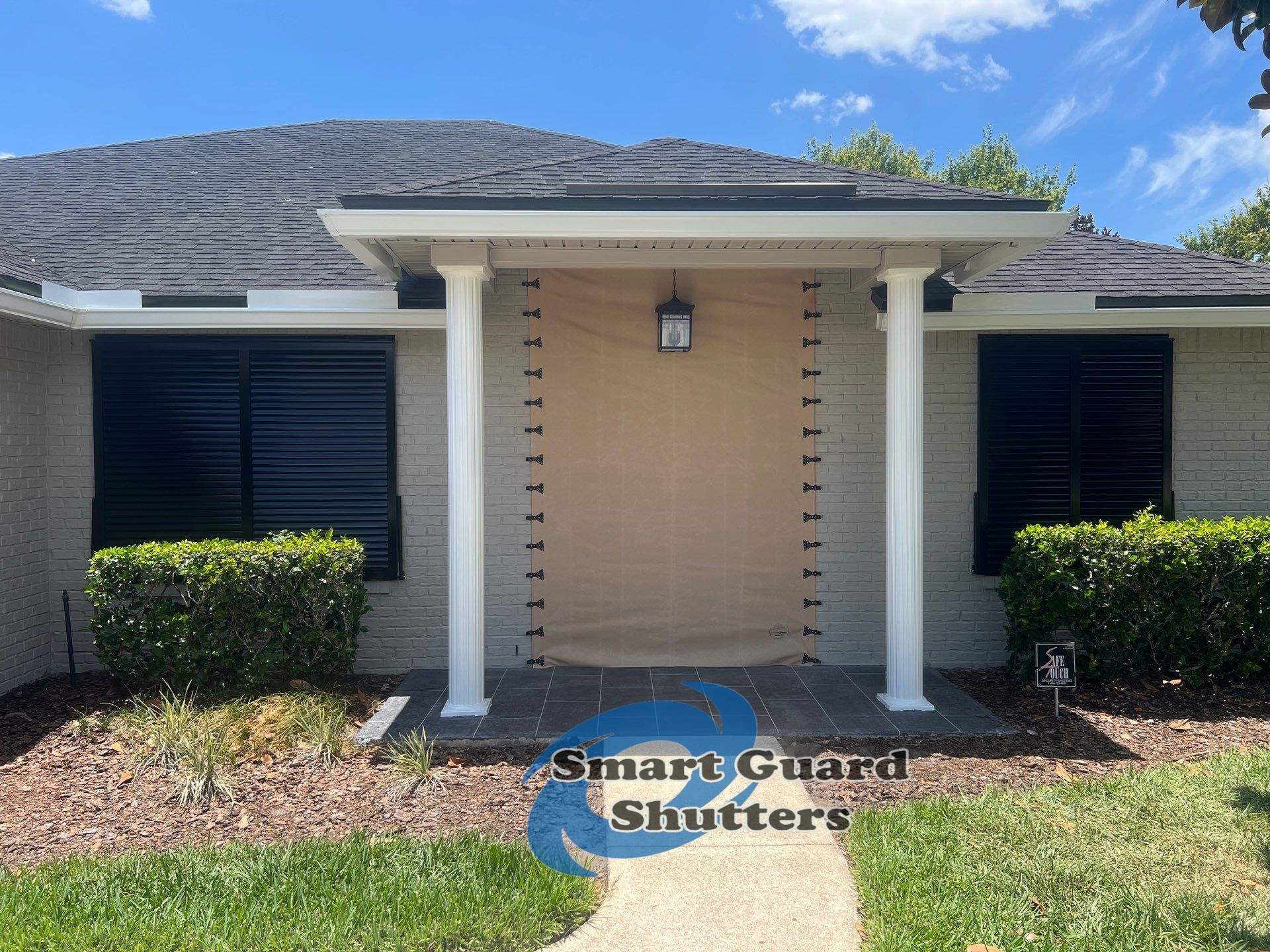 Hurricane Protection using Bahamas in Traffic Black and Fabric in Tan by Smart Guard Shutters