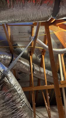 Attic interior showing ductwork and roof rafters.