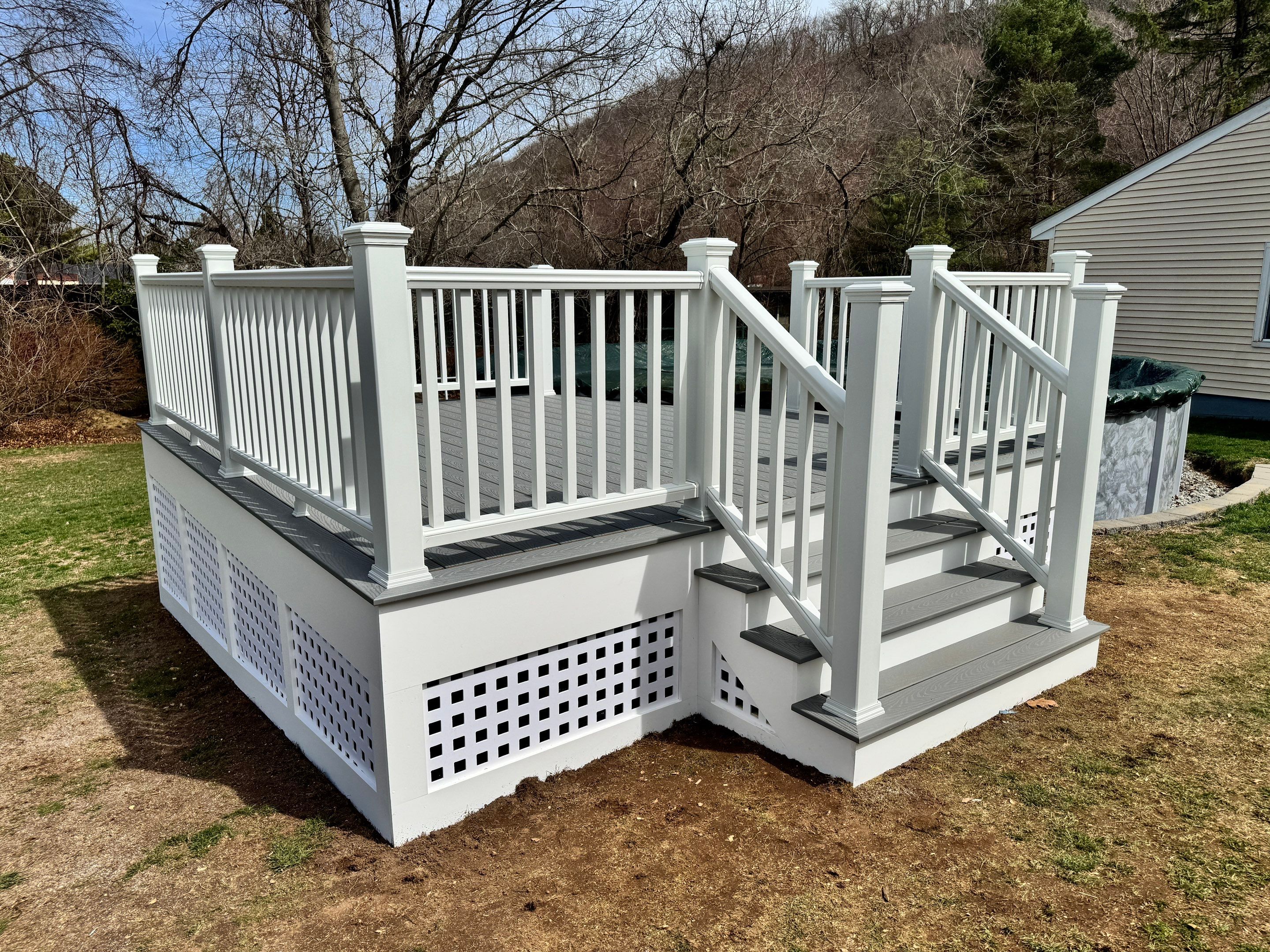 New pool deck using Trex Pebble Gray boards and White composite railings and lattice  by DiGiorgi Roofing and Siding Inc