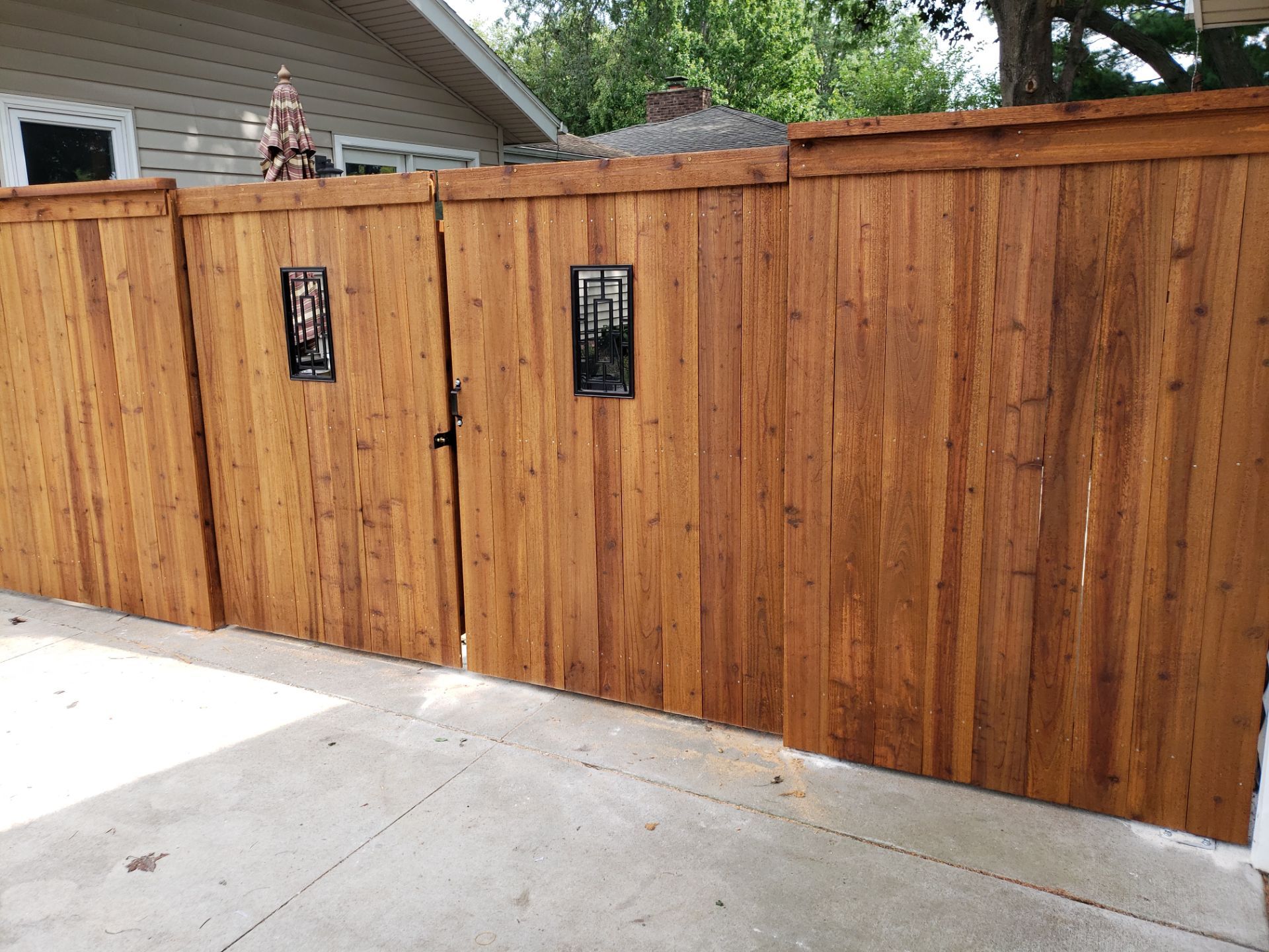 Custom Cedar Privacy Fence with Decorative Gate Windows in Cedar Falls by Perfect Picket Fence and Stain