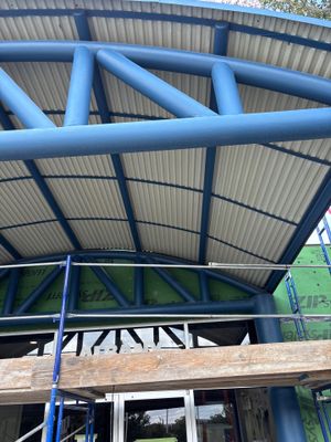 Curved metal roof on a blue steel support structure.