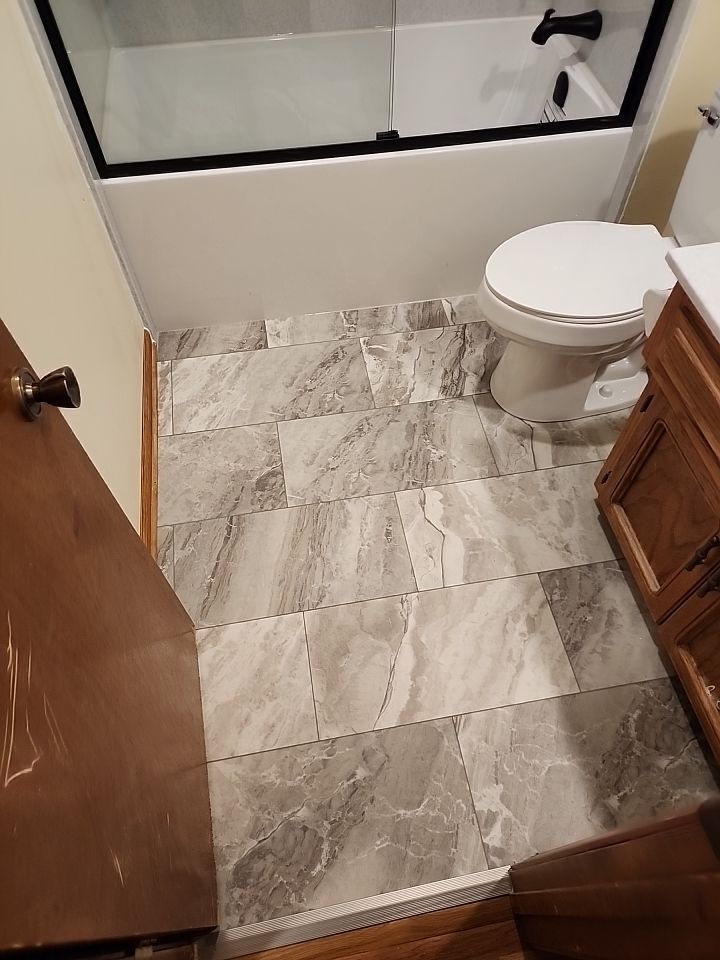 Bathtub, door, toilet, flooring, and countertop by The Shower Company
