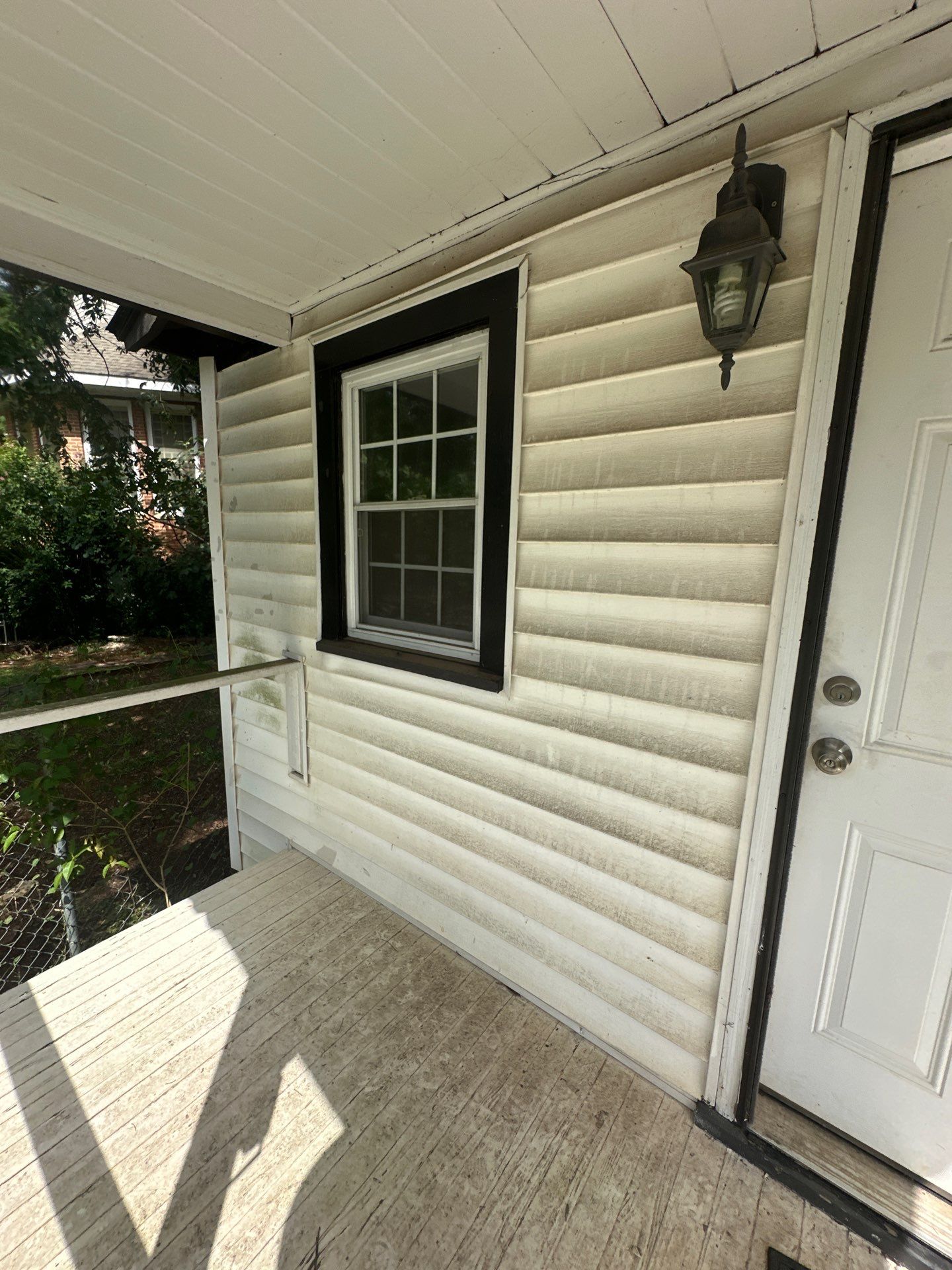 the image shows siding and a porch being cleaned to remove dirt and grime for a refreshed appearance