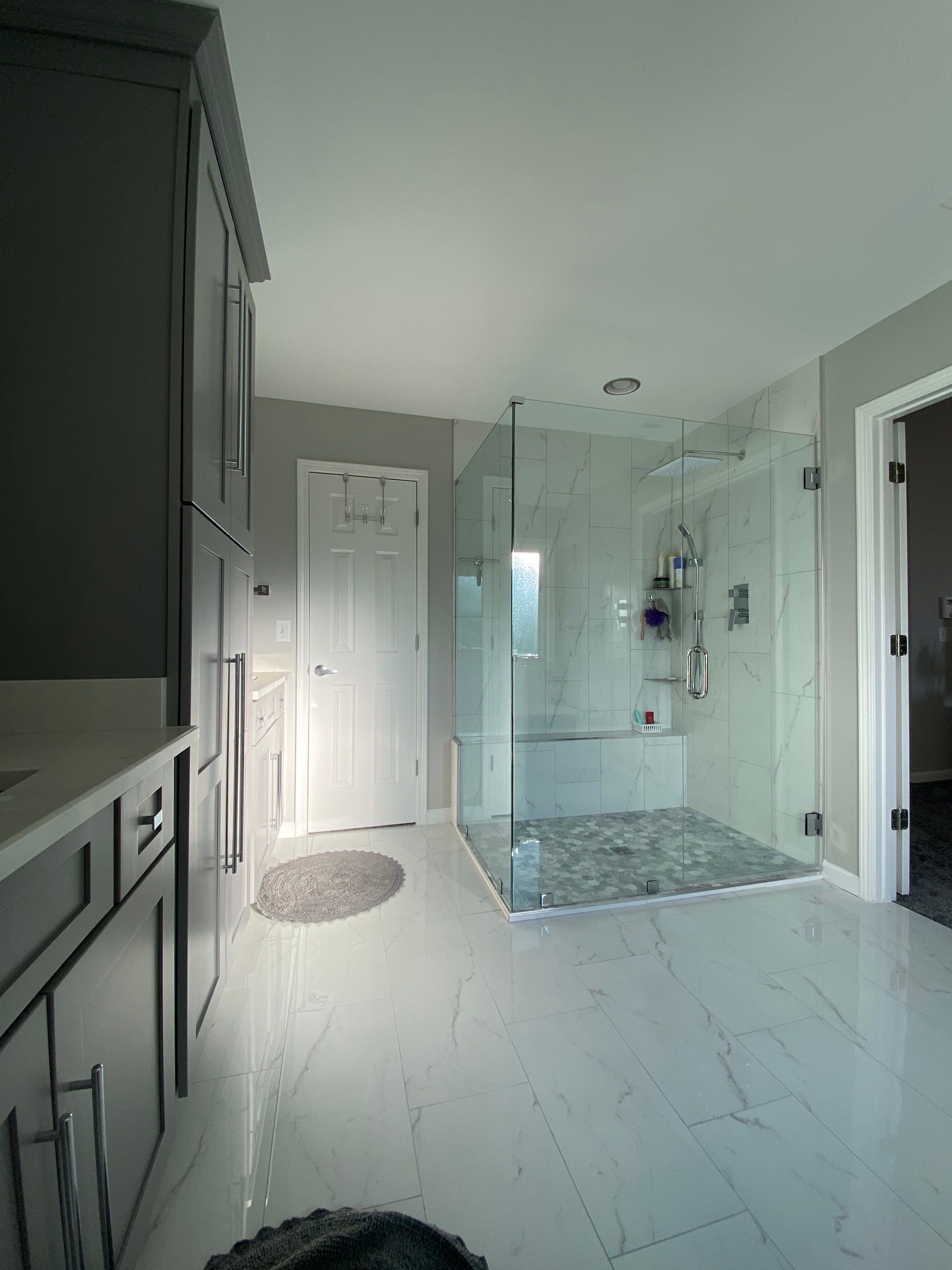 Master Bathroom Renovation Featuring Marble-Look Tile and Frameless Glass by Swift Home Renovations