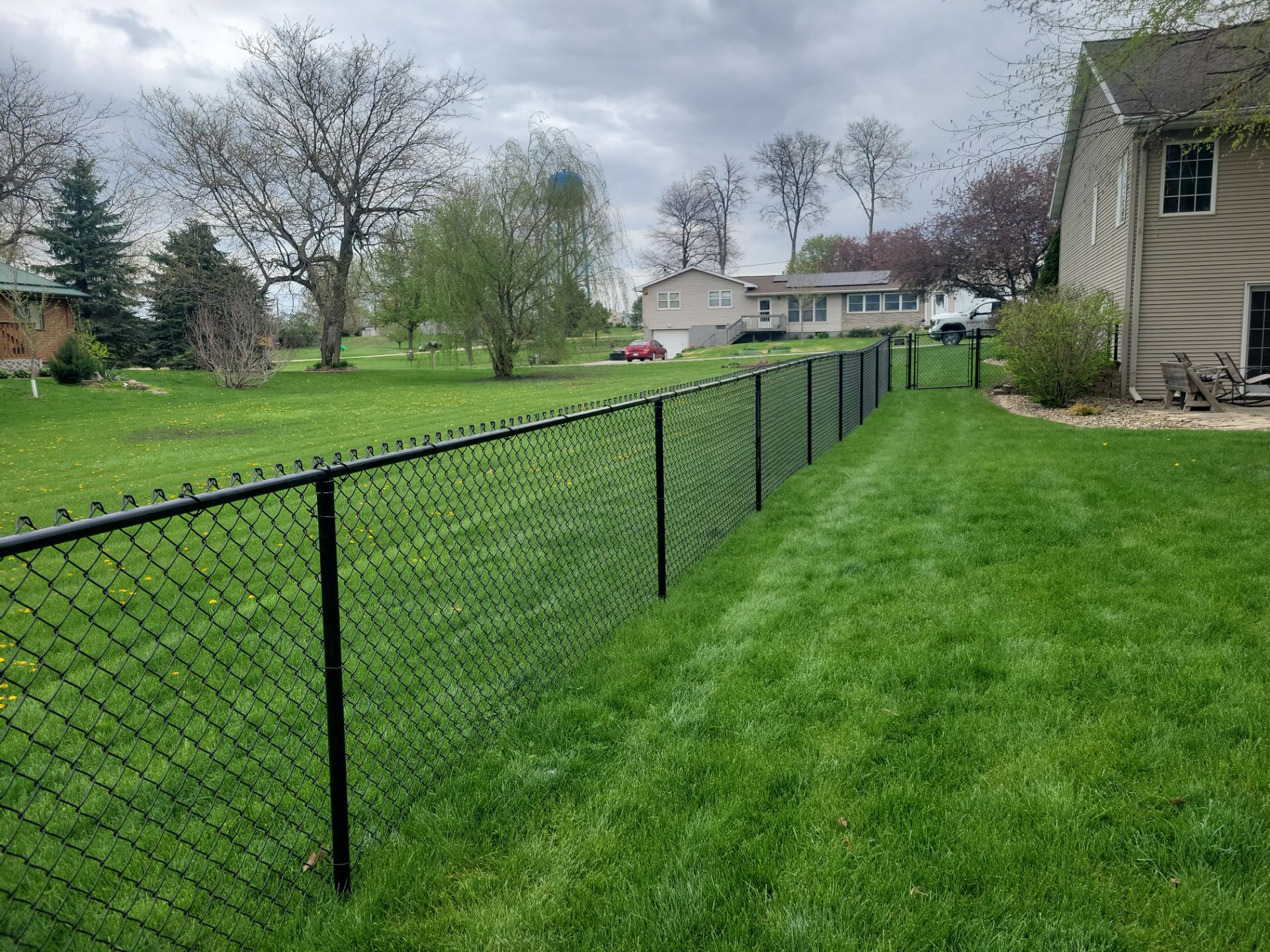 Residential Black Vinyl-Coated Chain Link Perimeter Fence in Garwin by Perfect Picket Fence and Stain