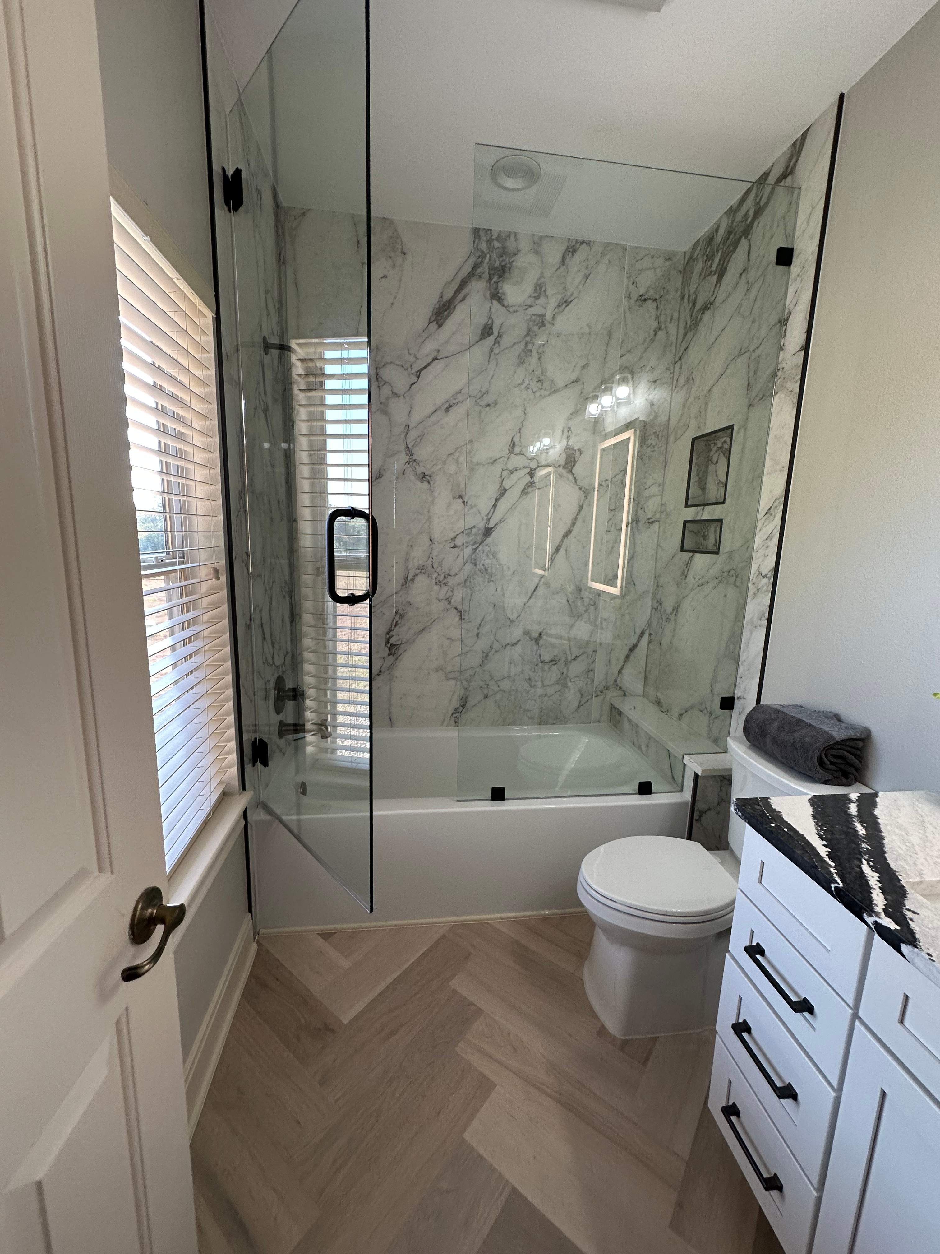 Boerne Guest Bathroom Remodel with Marble Tub Surround & Herringbone Flooring by Legacy Bath and Kitchen