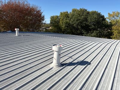 Completed corrugated metal roof with multiple vent pipes