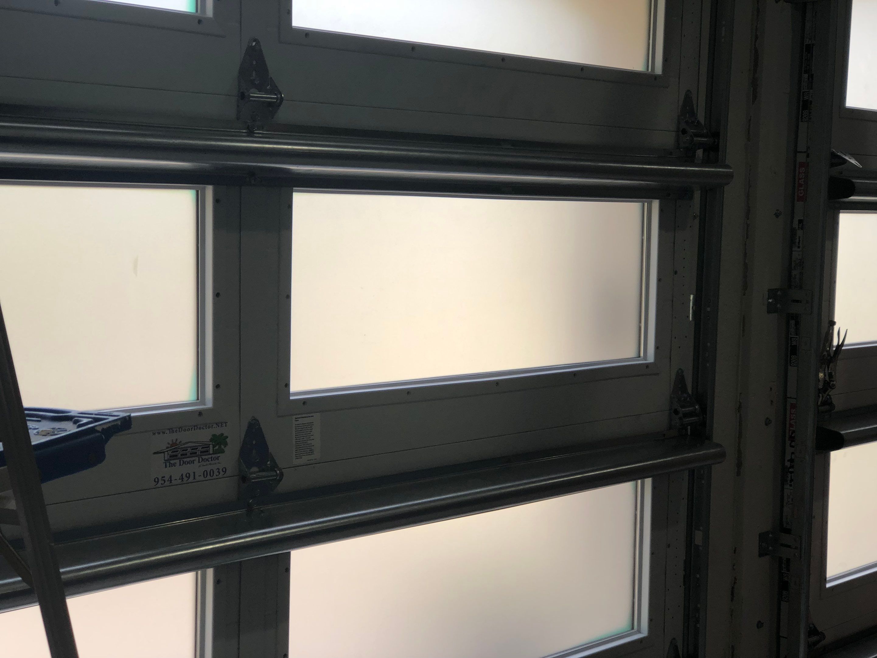 Modern Bronze Garage Door Installation With Frosted Glass in Boca Raton by The Door Doctor of South Florida, Inc.