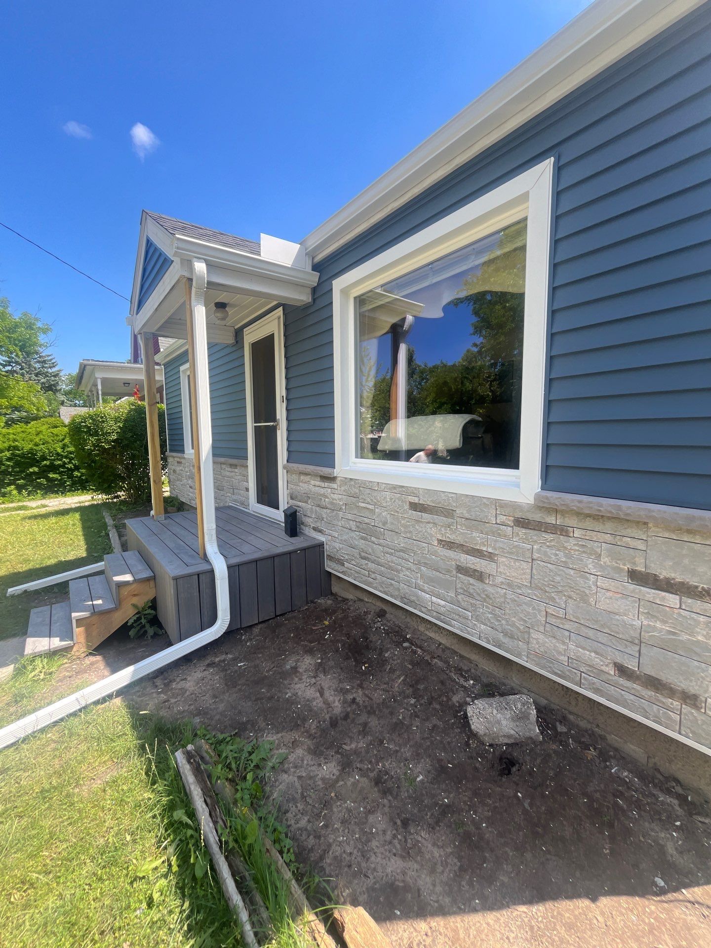 Blue Vinyl Siding and Versetta Stone Exterior Remodel in Bay City by Great Lakes Home Design LLC