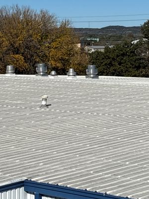 Metal roof with several vents and distant trees