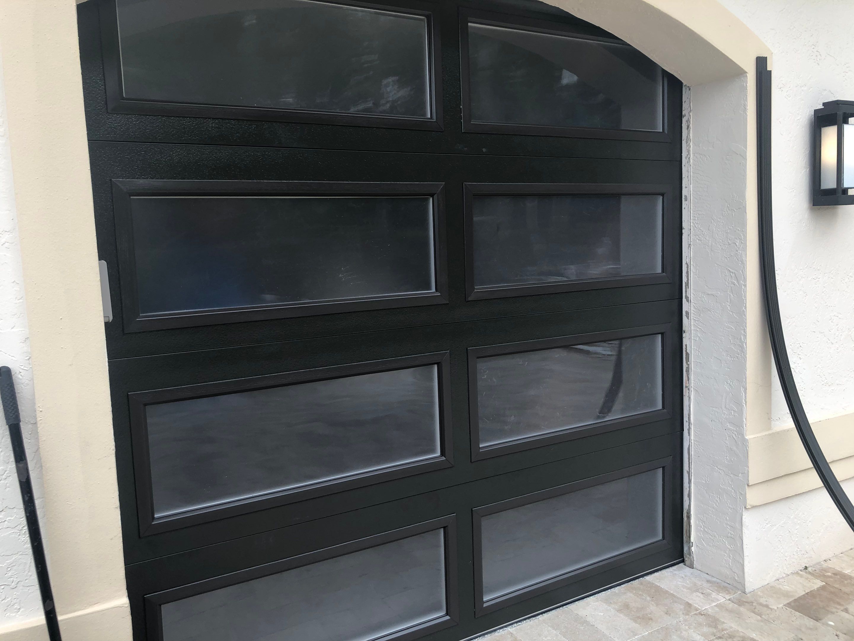Modern Bronze Garage Door Installation With Frosted Glass in Boca Raton by The Door Doctor of South Florida, Inc.