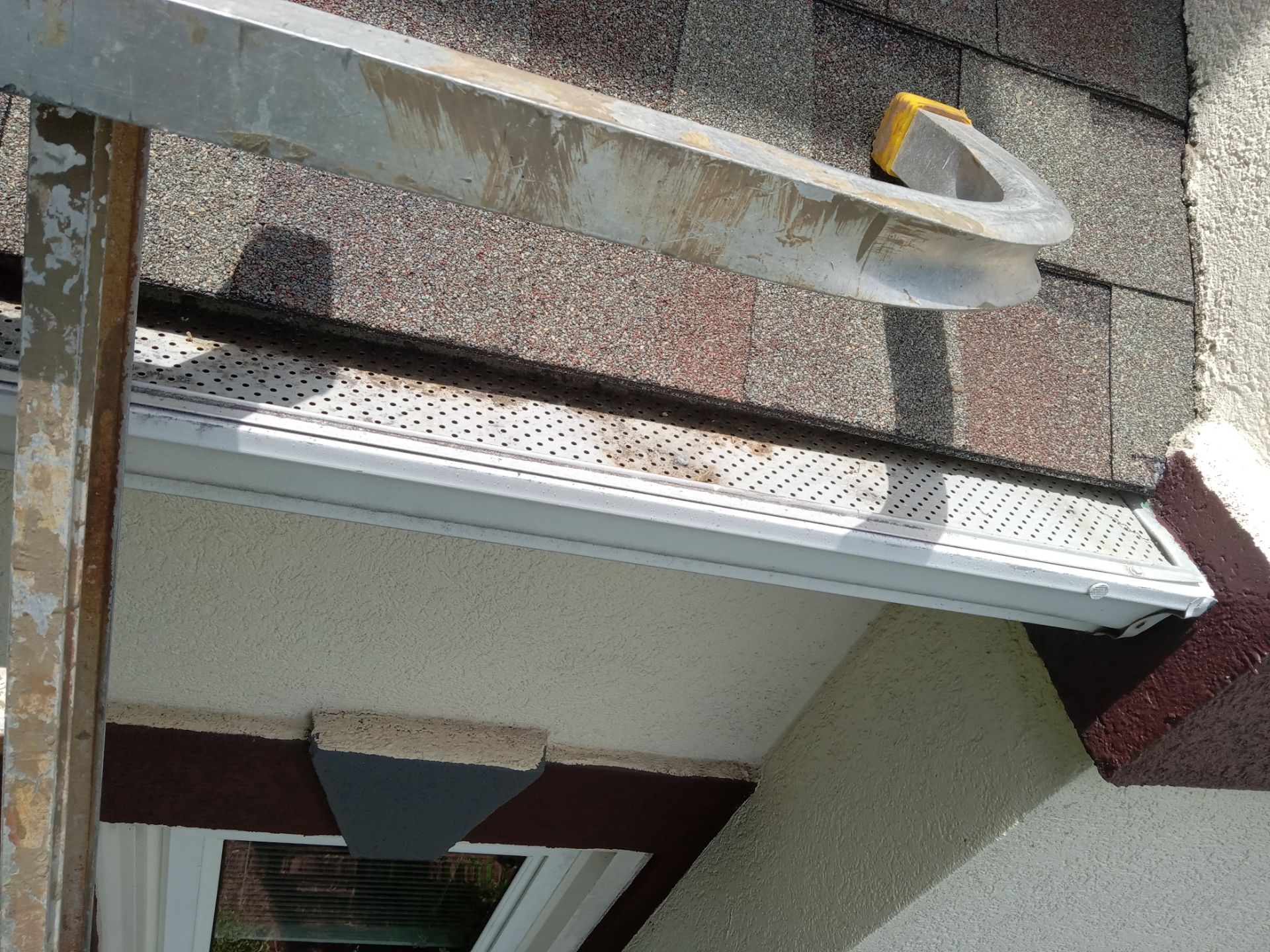 the image shows a ladder leading up to a residential gutter system where cleaning is in progress the gutters appear to have debris and stains that are in the process of being removed likely the pressure washing company is performing gutter cleaning services which involves removing leaves twigs and other debris that has accumulated this can help prevent blockages and improve water flow through the gutters it may also include washing away stains and mildew from the outside of the gutters to enhance their appearance and maintain the home's exterior