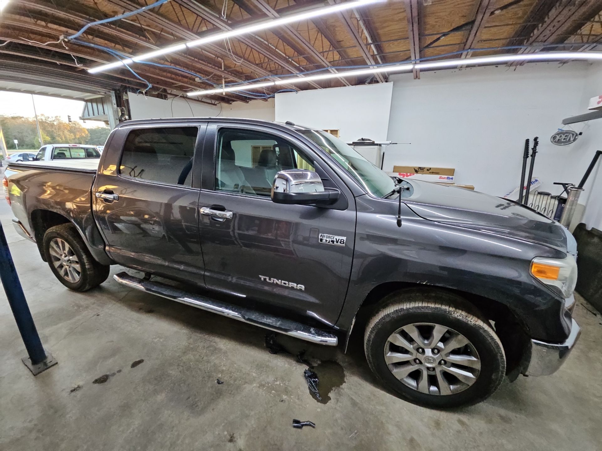 the service being done is window tinting on a grey toyota tundra the tinting process involves applying a specialized film to the windows to reduce glare and heat while providing added privacy this truck is likely being prepared for enhanced comfort and aesthetics with the new tint being carefully installed in a clean and organized environment of the tinting shop