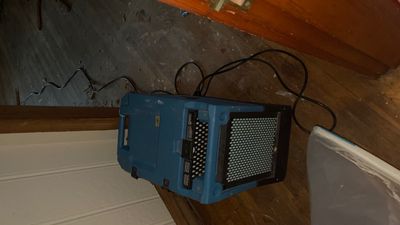 Blue drying equipment set on a wood floor with power cords nearby.