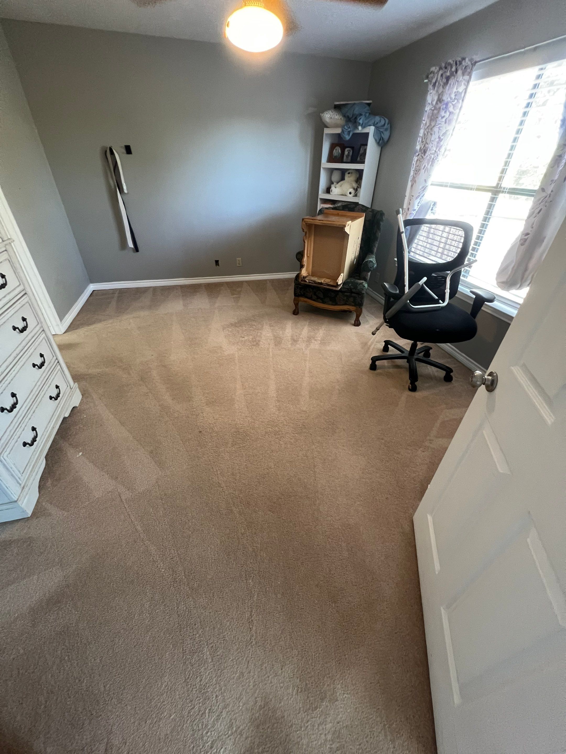 the service being done is carpet cleaning in a bedroom with light colored carpet and minimal furniture present