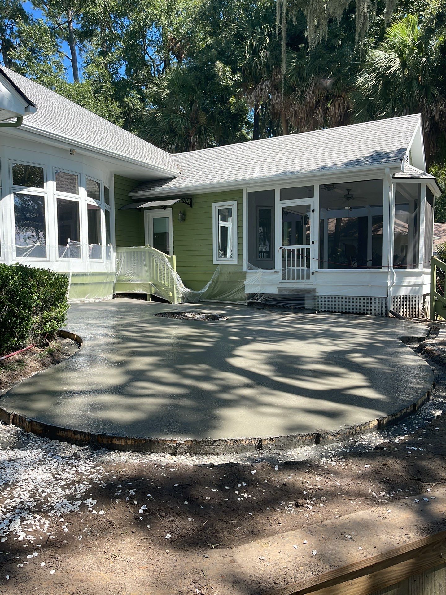 Exposed Aggregate Patio with Brick Inlays and Retaining Wall in Okatie by Lowcountry Scapes, LLC