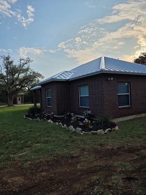 Completed standing seam metal roof on a red brick home.