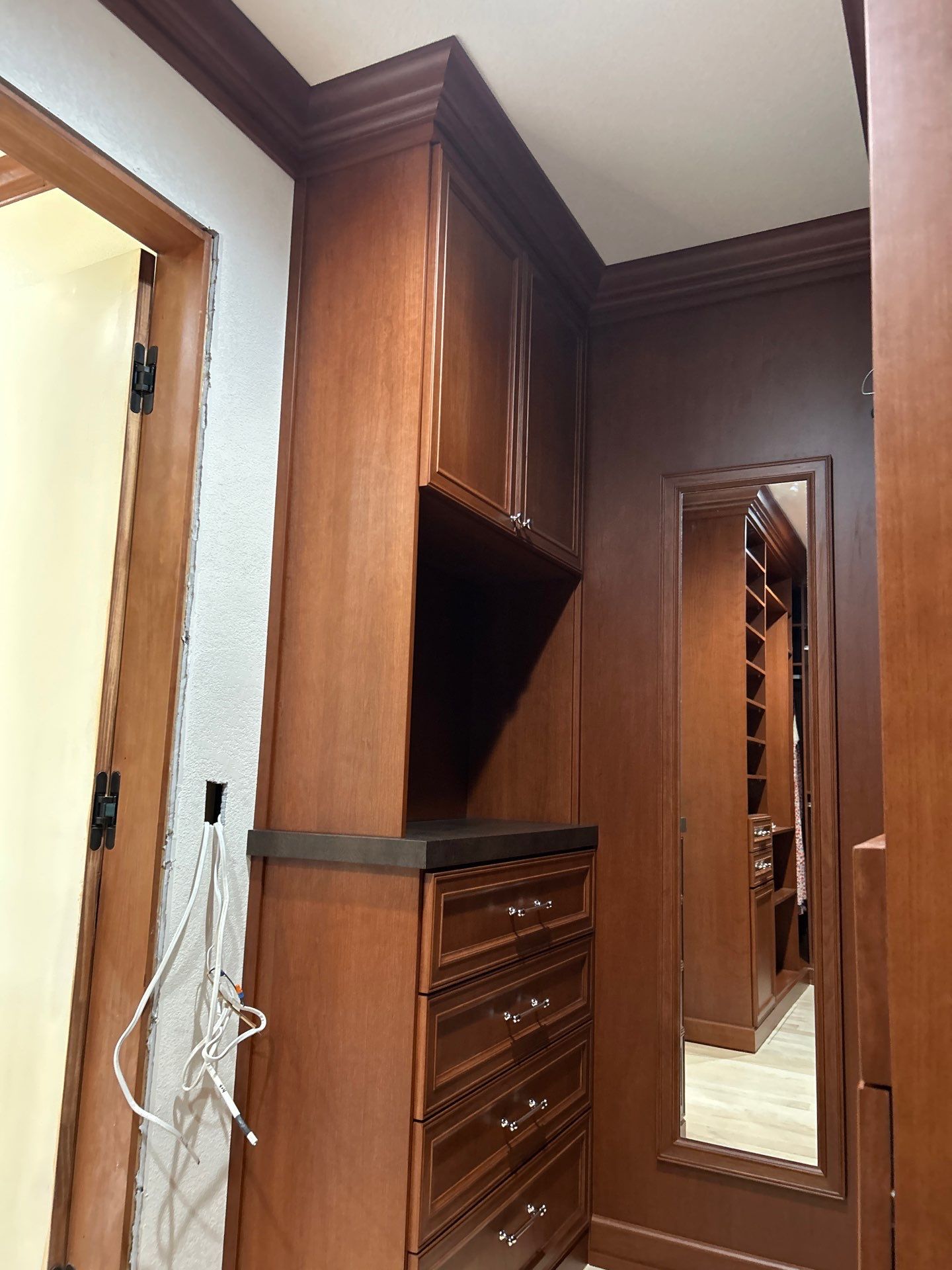 Stained Cherry Wood Primary Closet by Concept 32, Inc.
