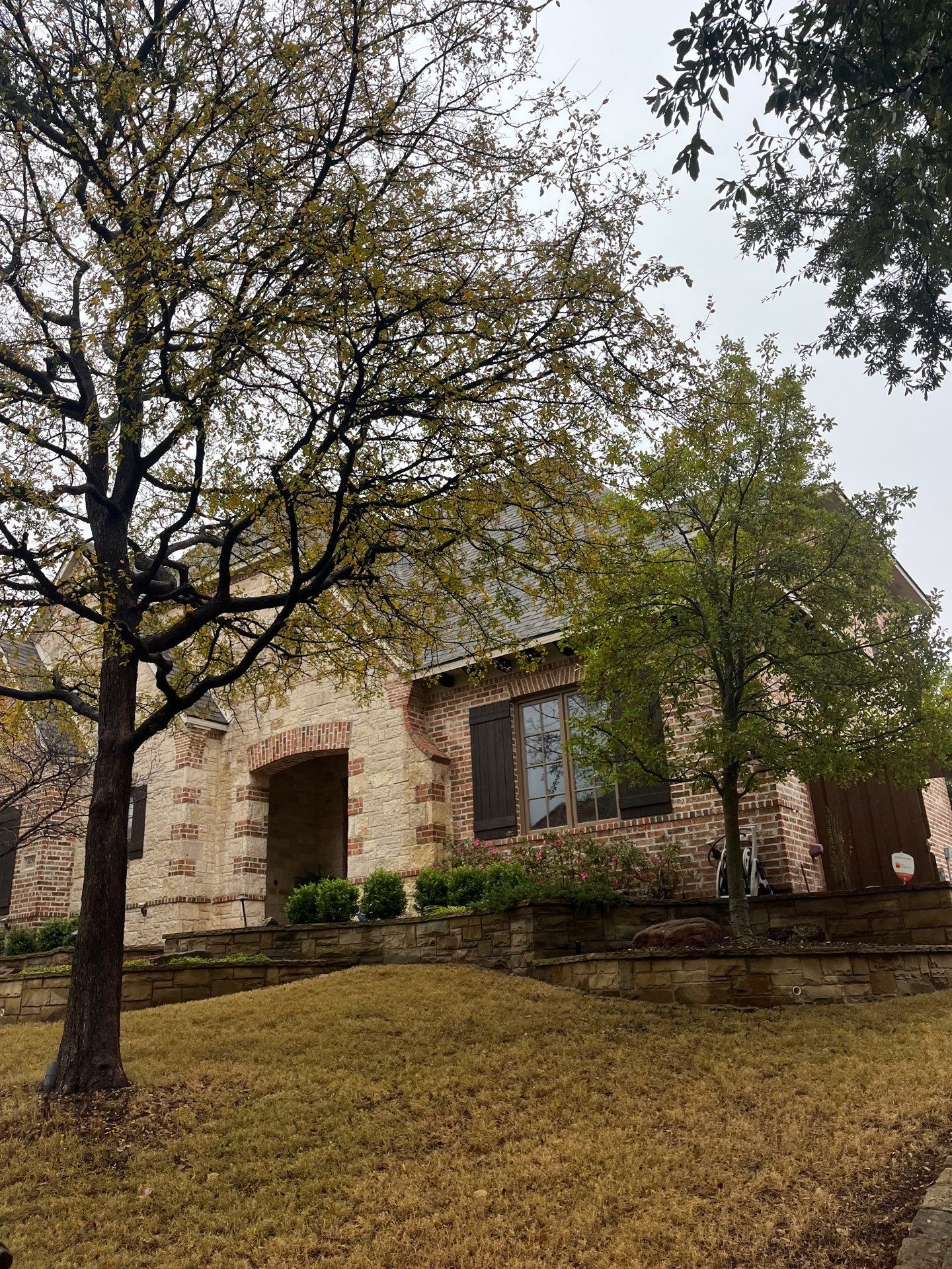 Light red brick/cream stone/espresso shutters with IKO Cornerstone by Tejas Roofworks + Restoration