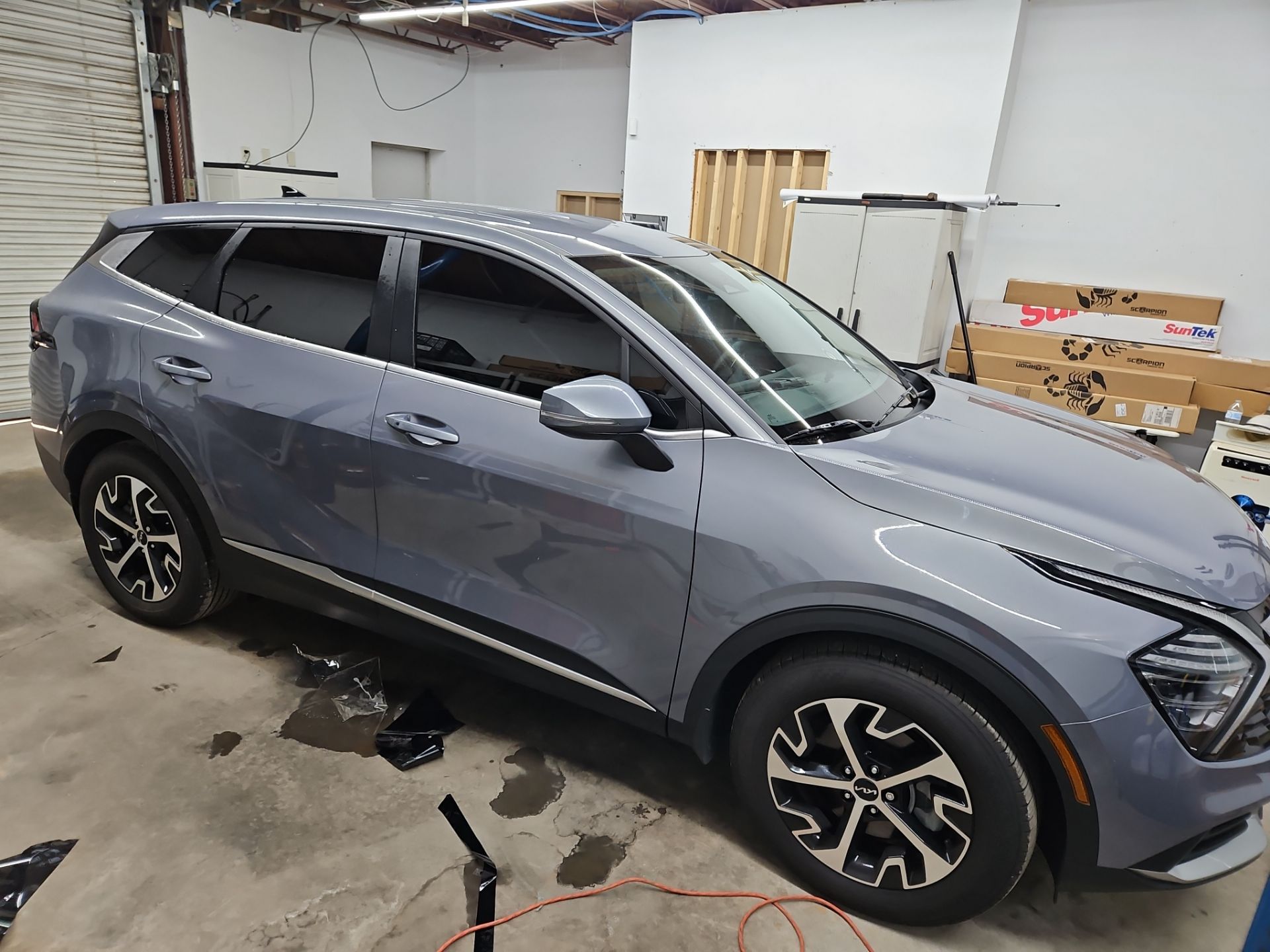 the image shows a vehicle that is undergoing window tinting service the windows appear to be partially tinted enhancing privacy and reducing glare the car is clean and well-maintained indicative of a professional service environment the tinting film remnants on the floor suggest an active installation process the overall look of the car after the tint will be more polished and stylish