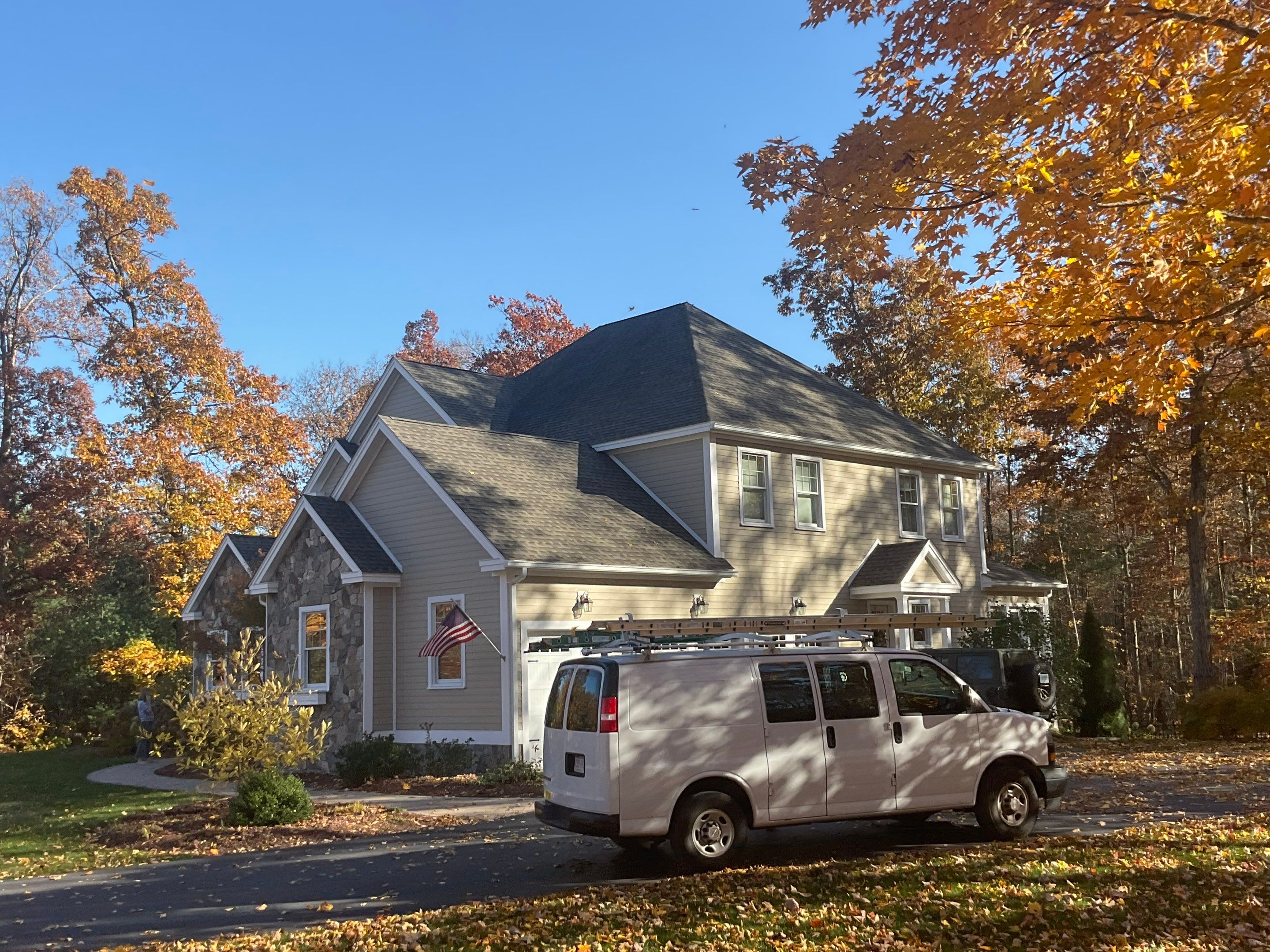 the service shown is house washing and potential roof cleaning in a residential area surrounded by autumn leaves