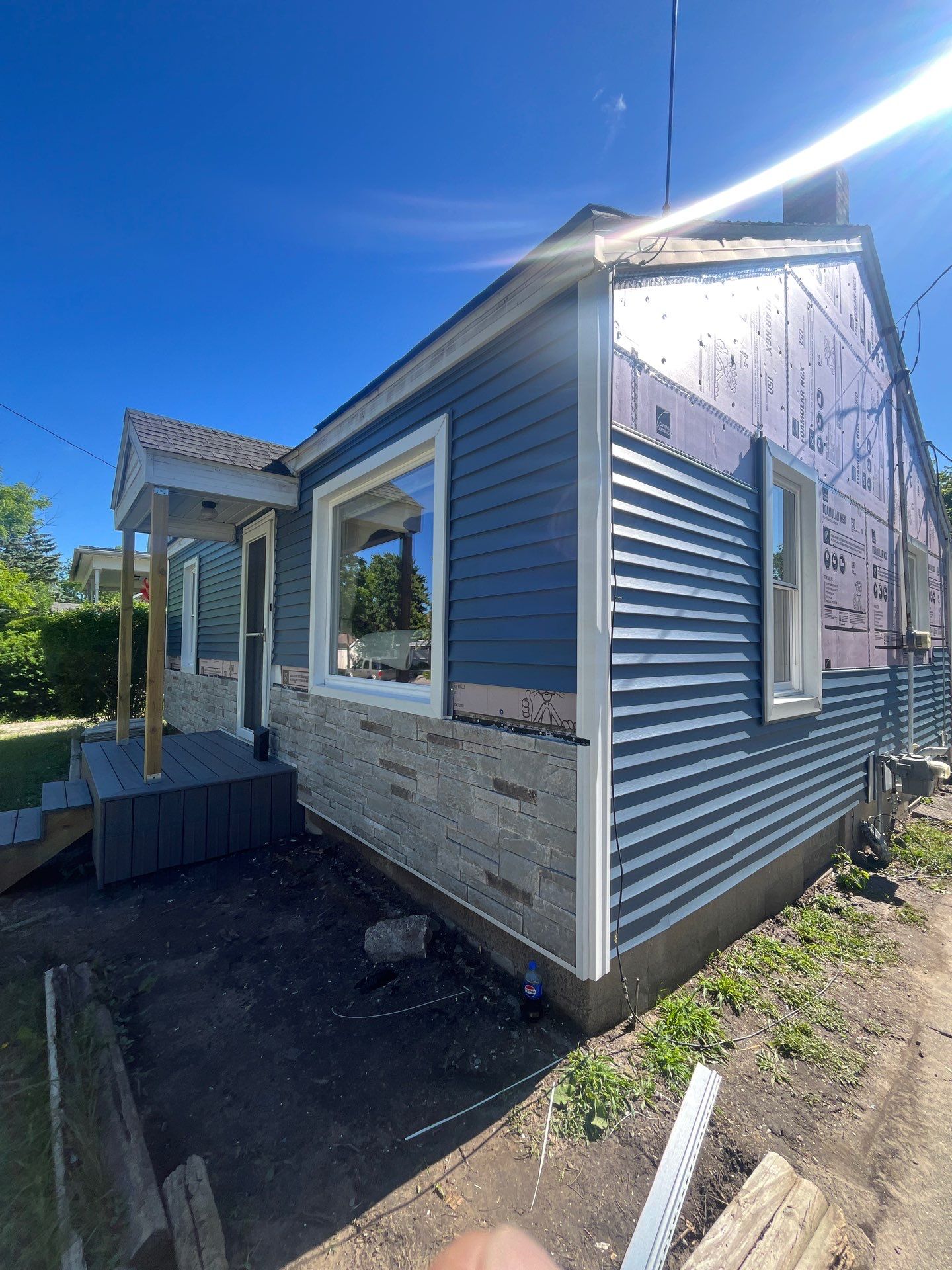 Blue Vinyl Siding and Versetta Stone Exterior Remodel in Bay City by Great Lakes Home Design LLC
