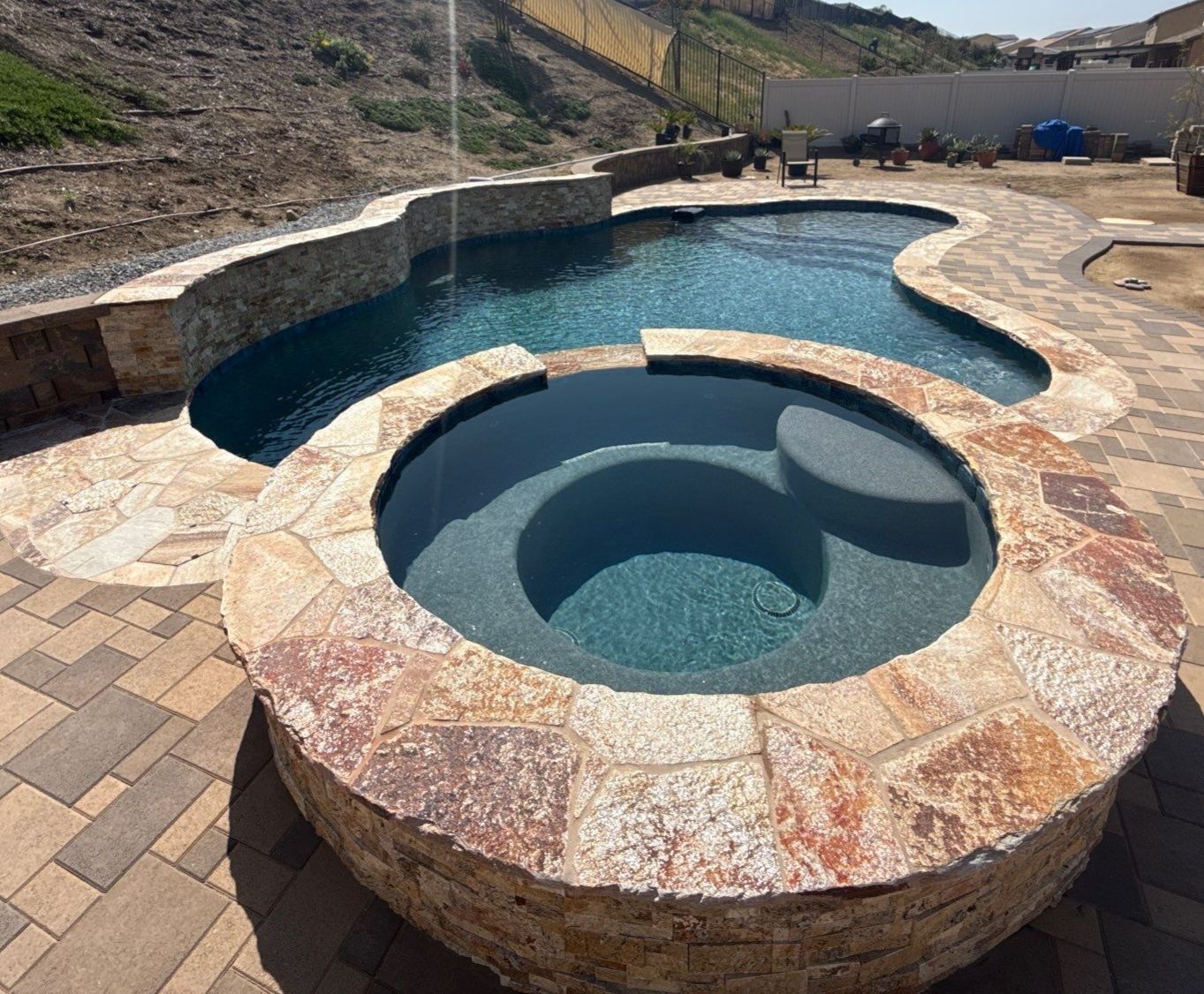 Freeform pool and spa with paver decking by Premier Pools and Spas Temecula