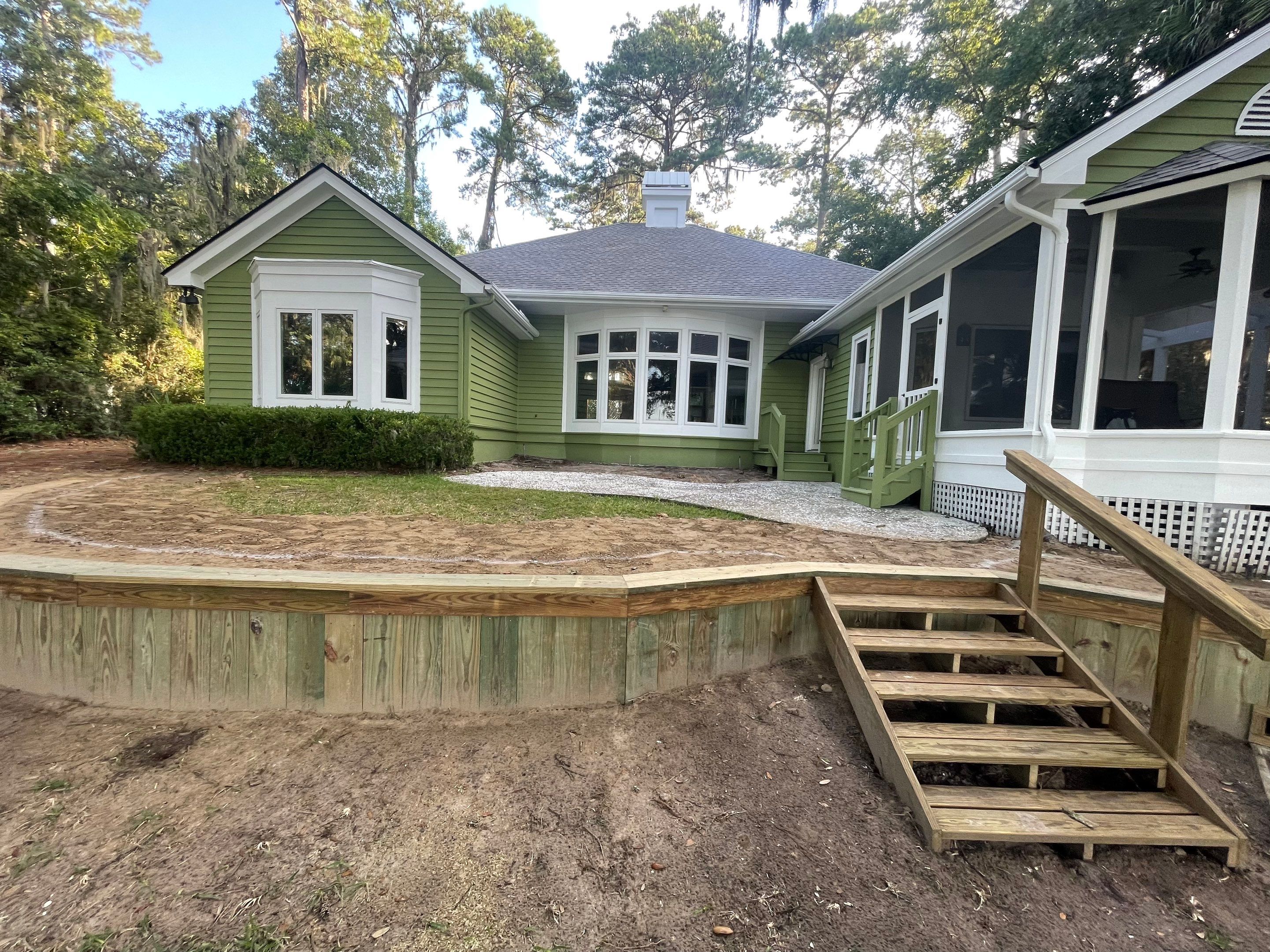 Exposed Aggregate Patio with Brick Inlays and Retaining Wall in Okatie by Lowcountry Scapes, LLC