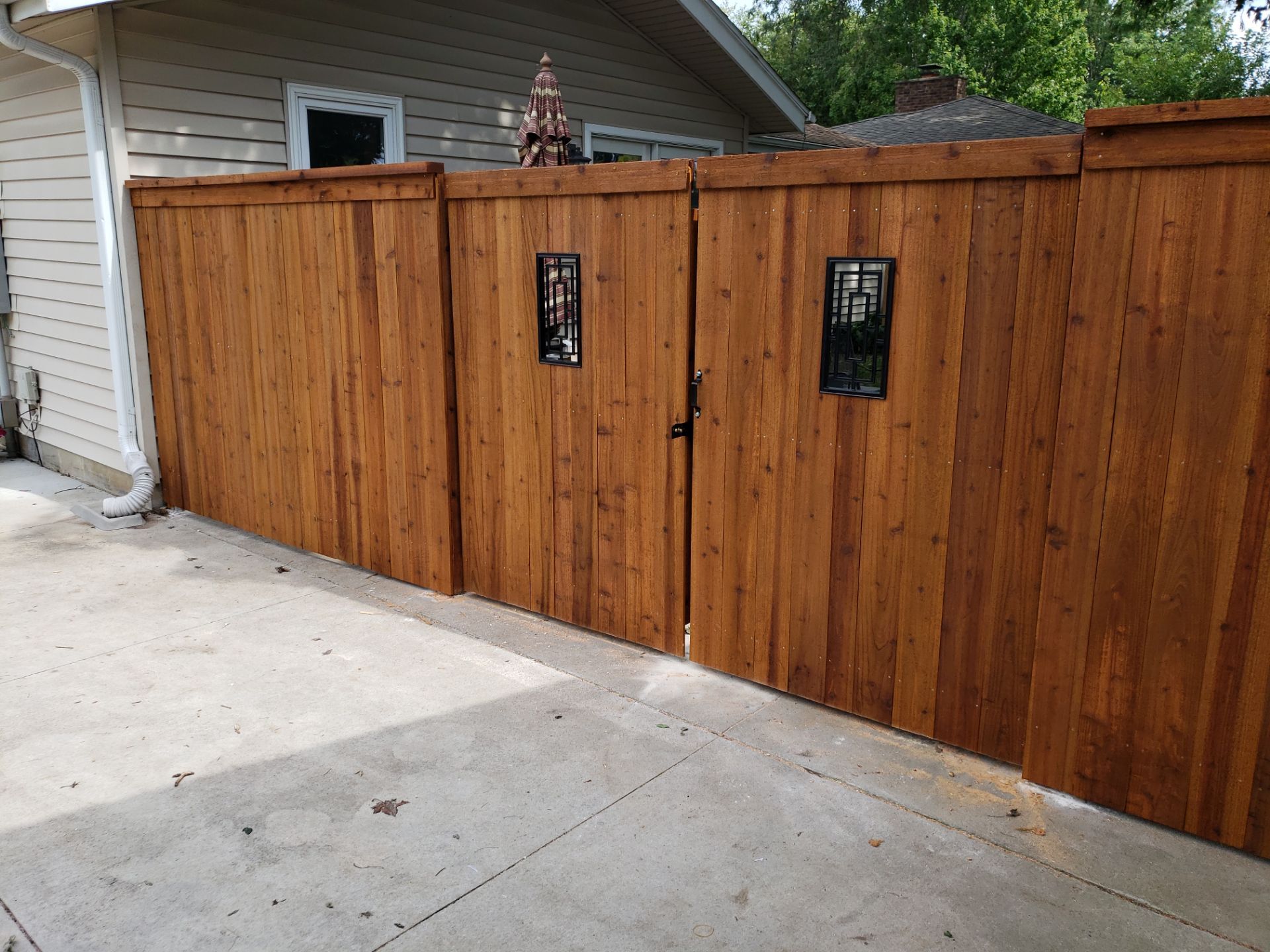 Custom Cedar Privacy Fence with Decorative Gate Windows in Cedar Falls by Perfect Picket Fence and Stain