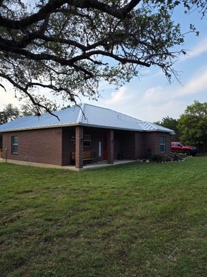 Standing seam metal roof on brick home at sunset.
