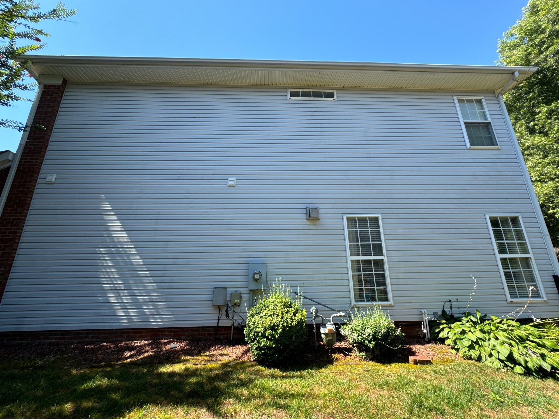 pressure washing cleaning siding of a residential house in winston salem north carolina on a sunny day