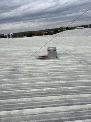Wide view of industrial metal roof with vent cap.