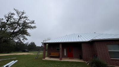 Completed standing seam metal roof on brick home.