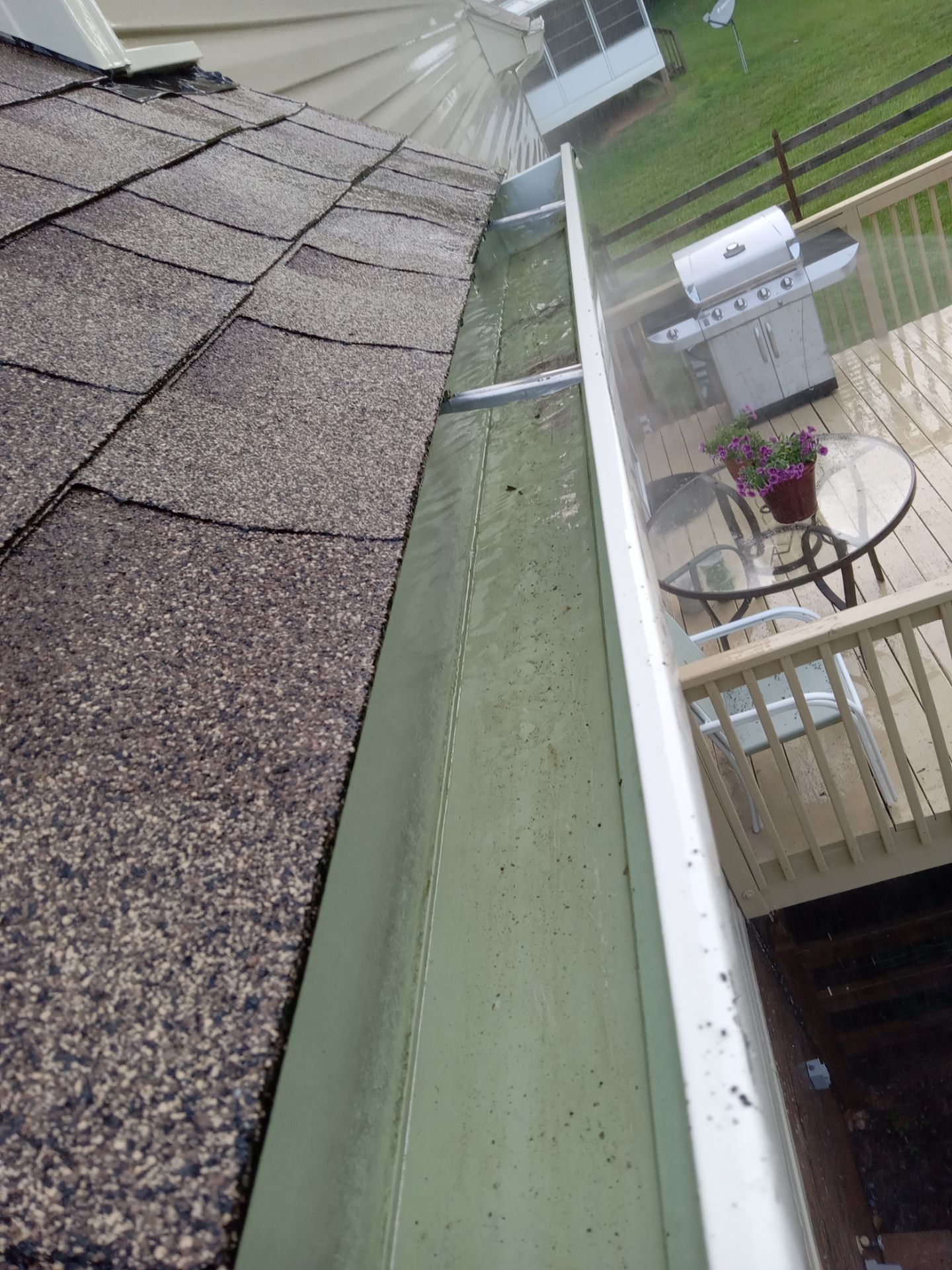 pressure washing company cleaning a home exterior specifically roof gutters and vinyl siding to remove dirt and algae