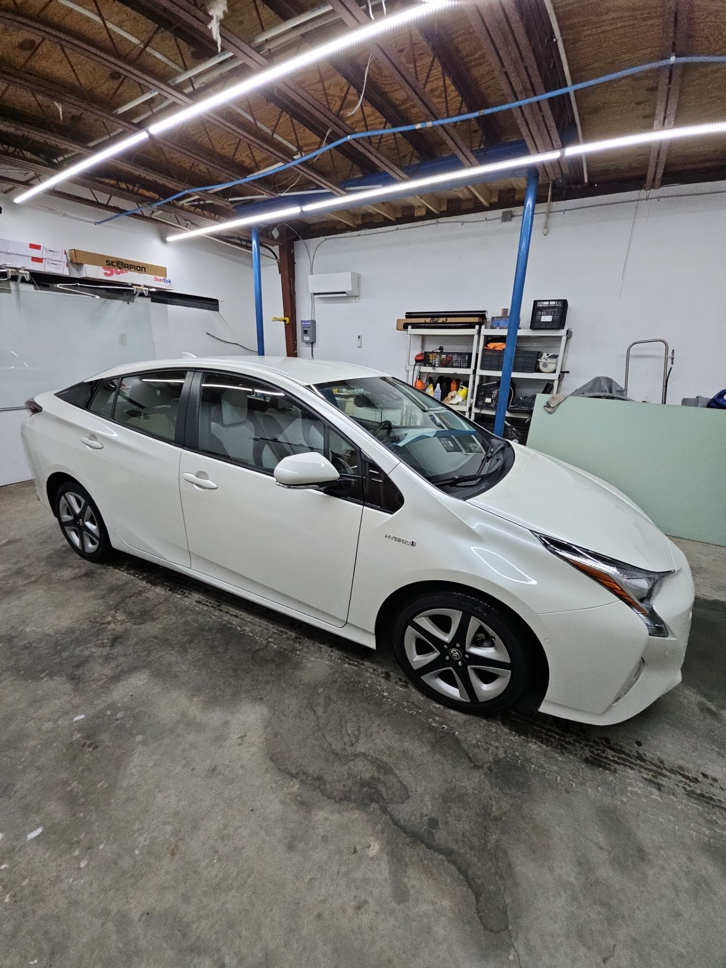 the service being done is window tinting on a white toyota prius the tint is applied to enhance privacy reduce heat and glare and protect the interior the car is inside a clean workspace indicating professional installation the process involves cleaning the windows preparing the surface and applying the tint film for a smooth finish