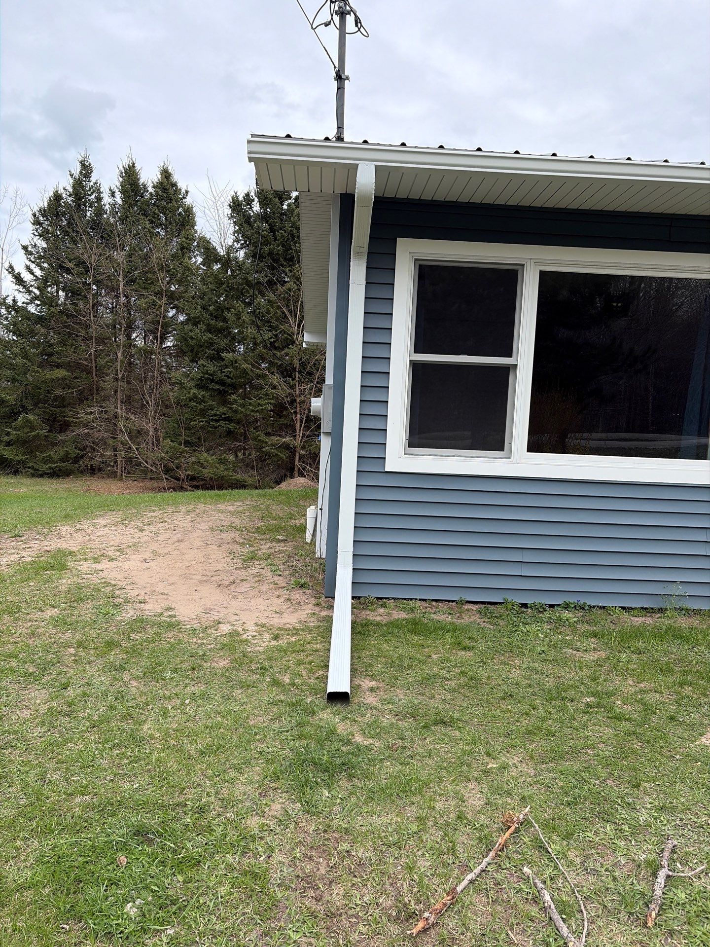 White Gutter and Downspout Installation for Boyne Falls Residential Property by Rainbow Seamless Systems