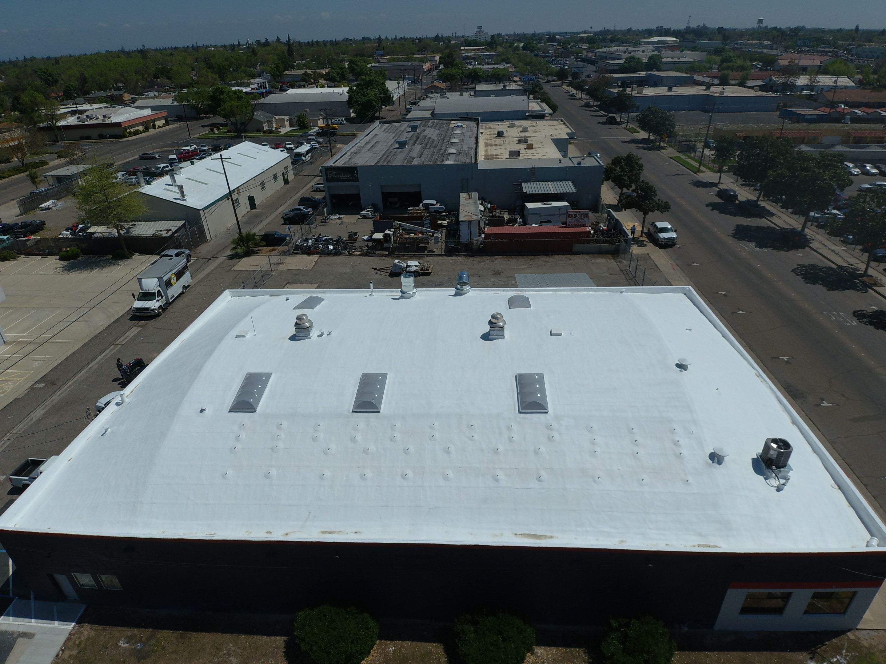 Spray foam and coatings using Conklin Benchmark/PUMA XL coatings on Auto Body Shop by Straight Edge Roofing Inc