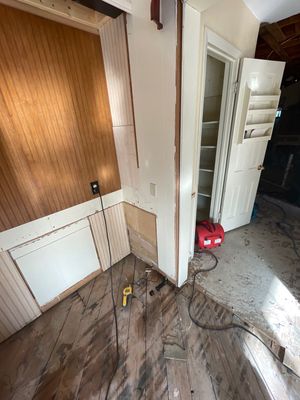 Interior room with lower wall sections removed, cords on the floor, and drying equipment nearby.