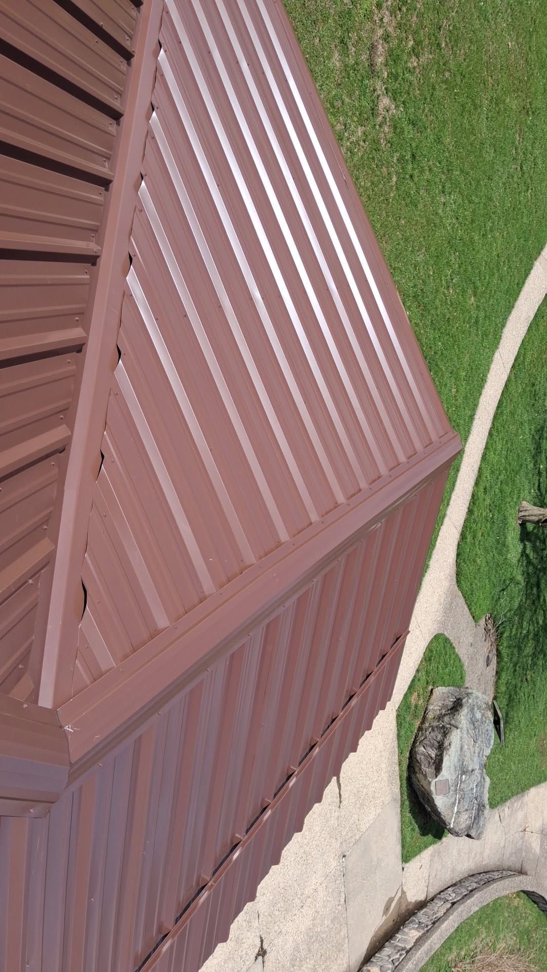 Brown R-Panel metal roof with solar by Atlas Roofing & Restoration