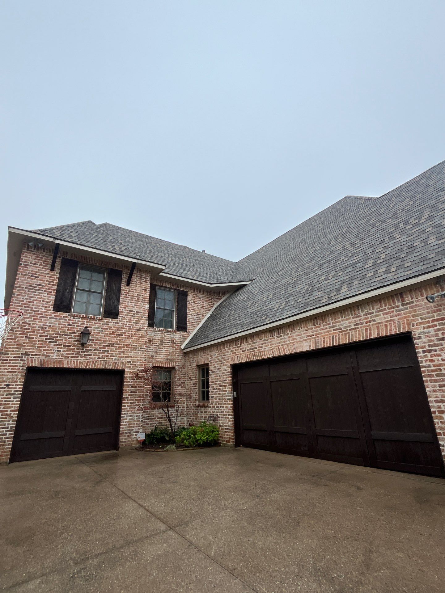Light red brick/cream stone/espresso shutters with IKO Cornerstone by Tejas Roofworks + Restoration