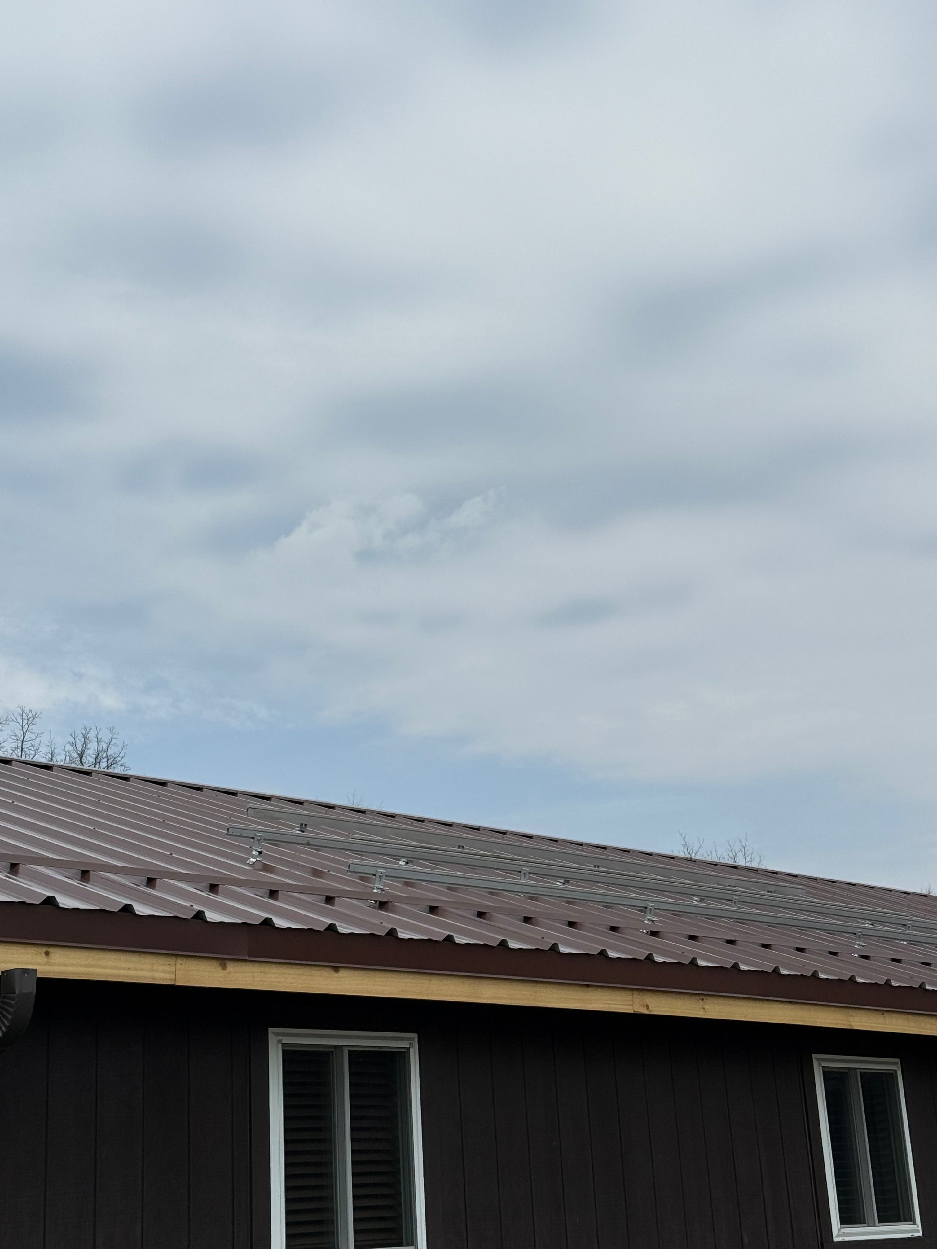 Brown R-Panel metal roof with solar by Atlas Roofing & Restoration