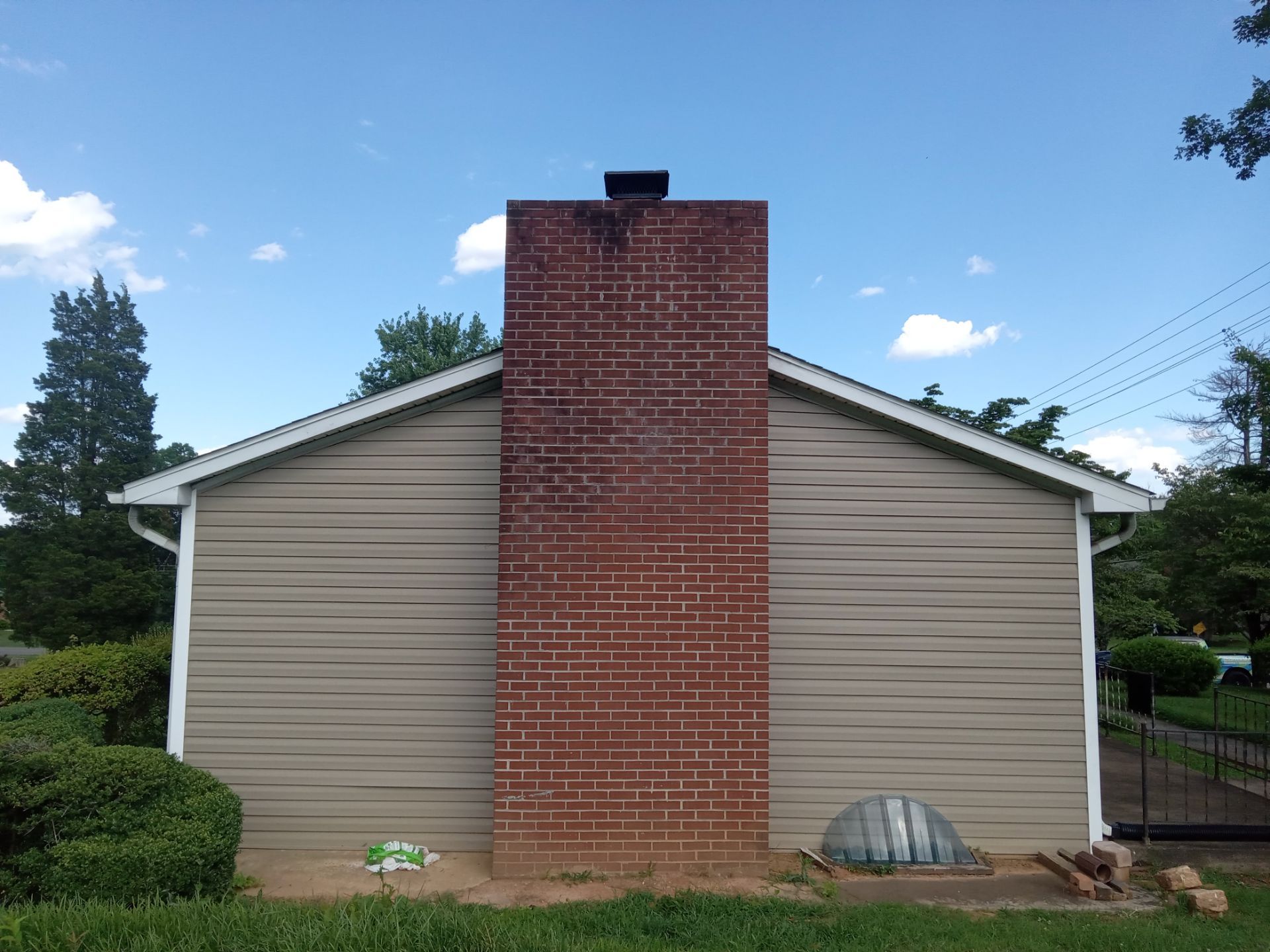 the pressure washing company based in kernersville nc is likely cleaning the exterior surfaces of this home the services shown include pressure washing the siding to remove dirt mildew or algae buildup that commonly accumulates on home exteriors over time they may also clean the brick surfaces of the chimney to restore its appearance the company might offer services to clean the gutters downspouts and other exterior features as well maintaining a clean and well-maintained exterior can help protect the home from the elements and improve curb appeal