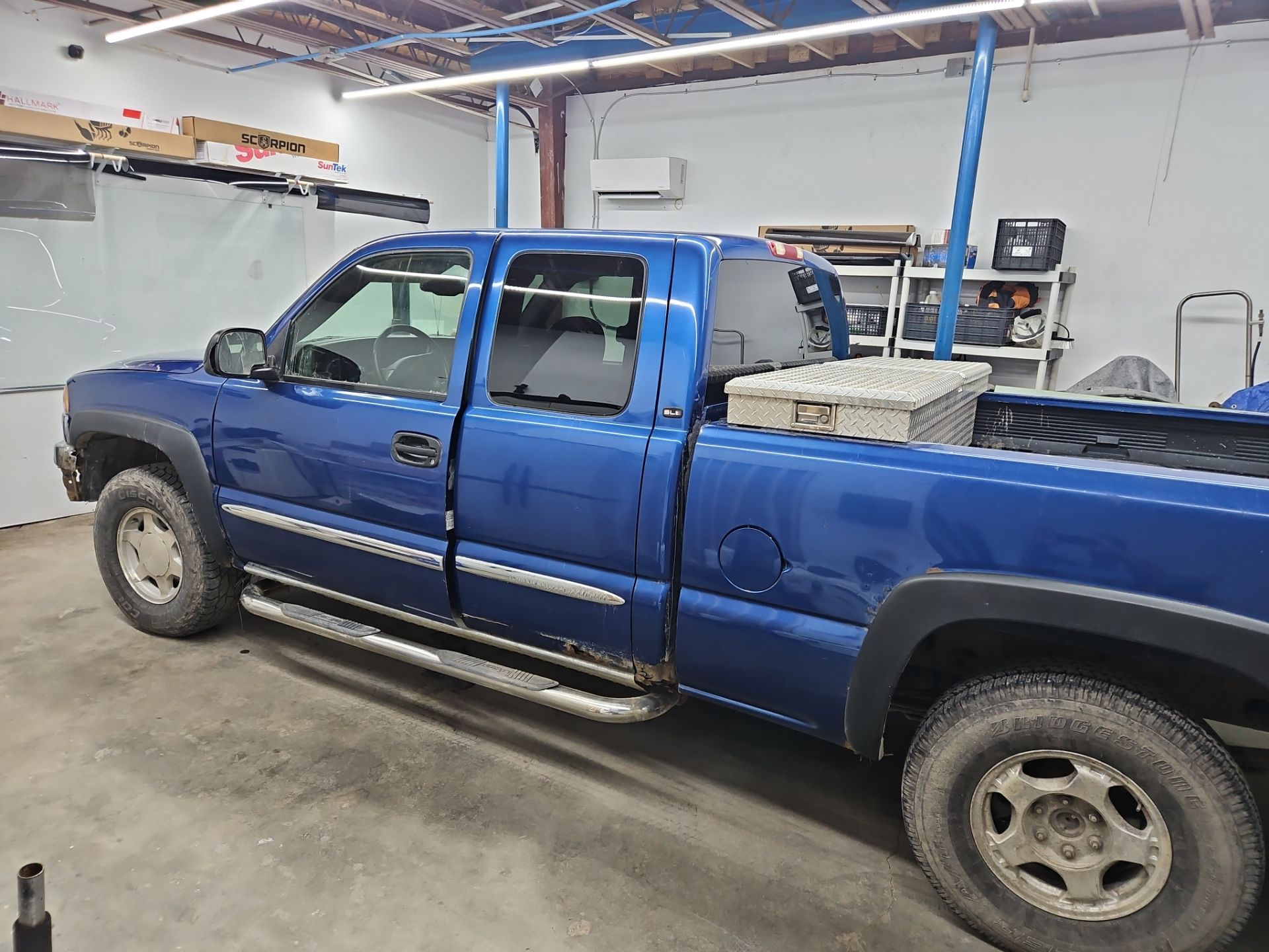 the service being done is window tinting on a blue pickup truck the workers are likely applying a layer of film to the windows to reduce glare and heat inside the vehicle this helps improve privacy and the aesthetic of the truck while also protecting the interior from sun damage the tinting process involves cleaning the windows thoroughly before applying the film and ensuring a smooth finish without bubbles or imperfections