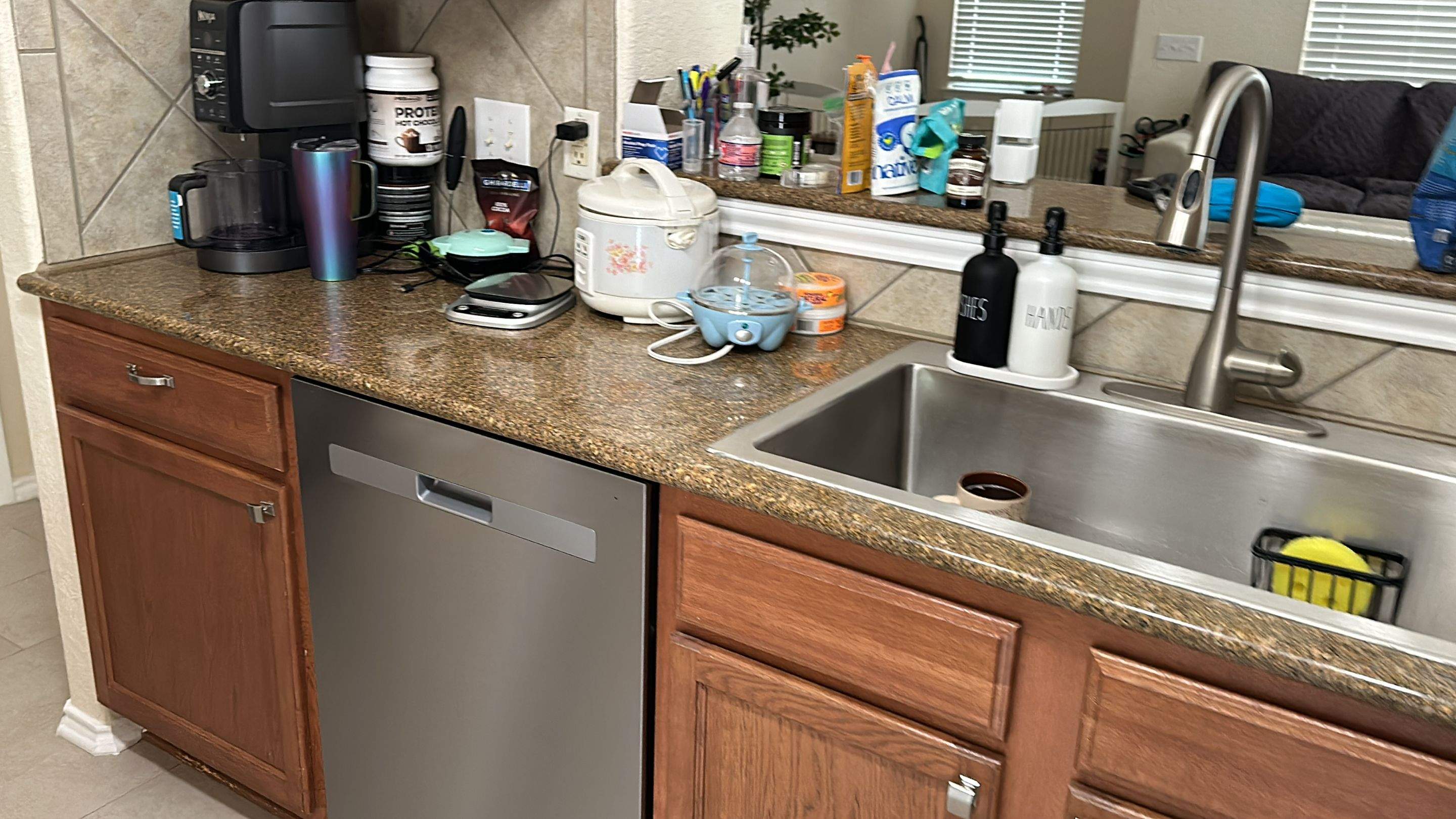 The old kitchen had a traditional builder-grade look with heavier wood cabinetry and busier finishes, while the new kitchen has a warm transitional design with cleaner lines, a brighter palette, and a more open, modern layout by Mena stone surfaces