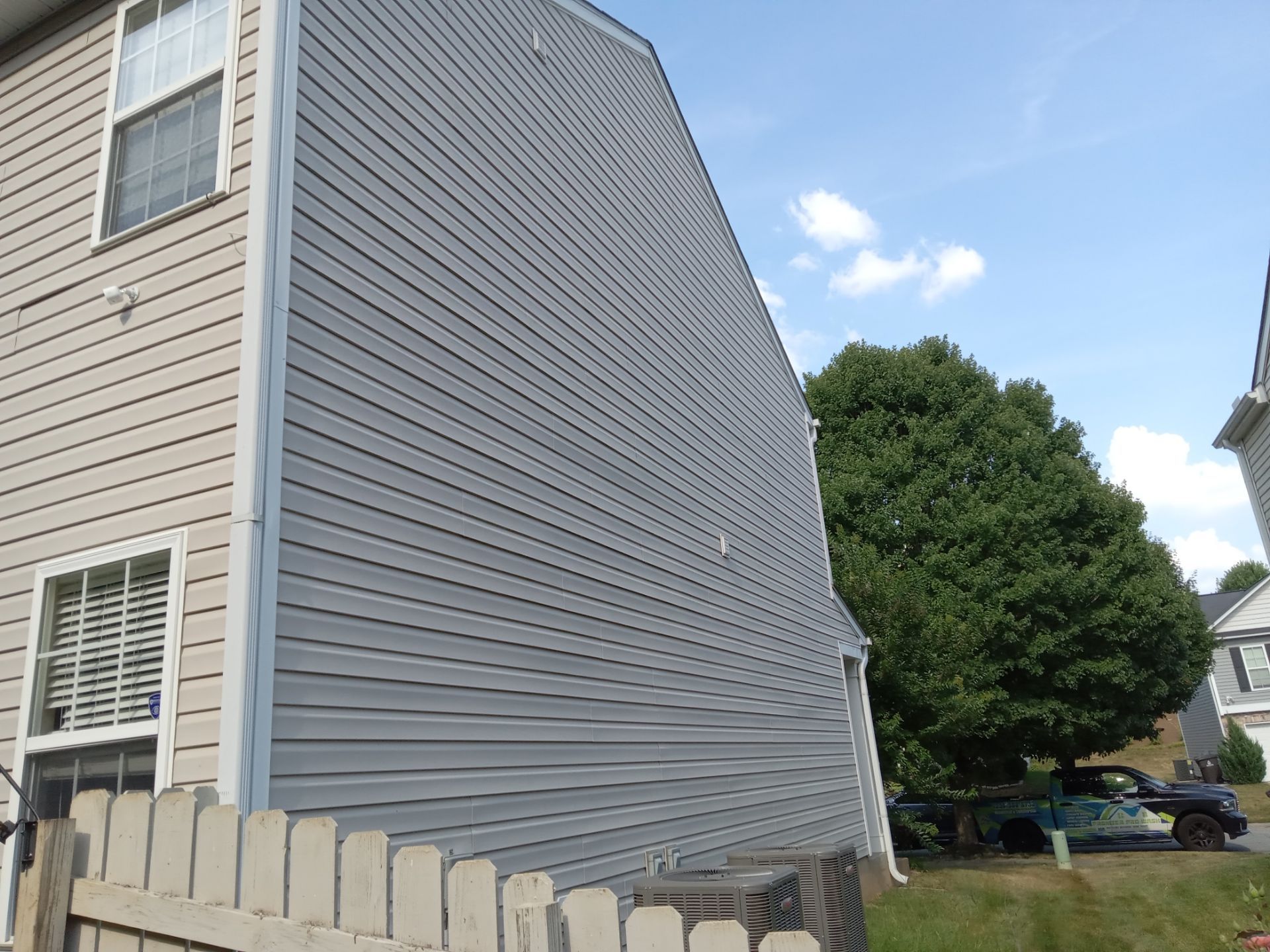 a pressure washing company is cleaning the exterior siding of a house and the adjacent fence in kernersville nc