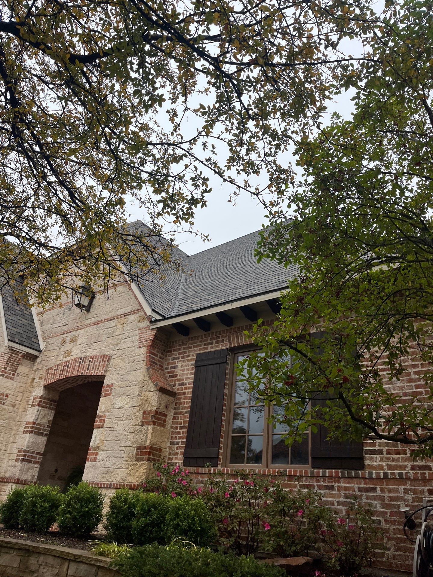Light red brick/cream stone/espresso shutters with IKO Cornerstone by Tejas Roofworks + Restoration