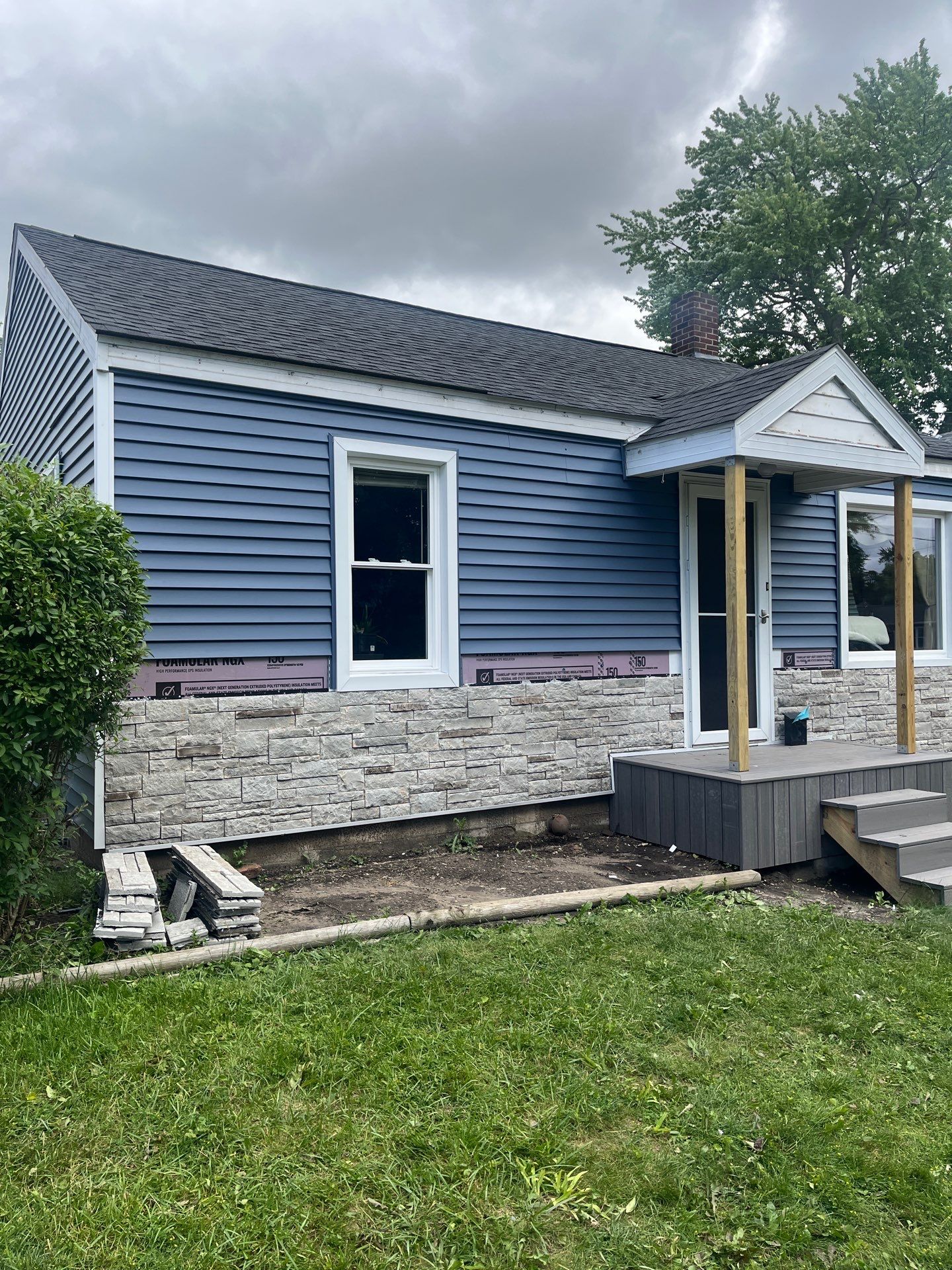 Blue Vinyl Siding and Versetta Stone Exterior Remodel in Bay City by Great Lakes Home Design LLC