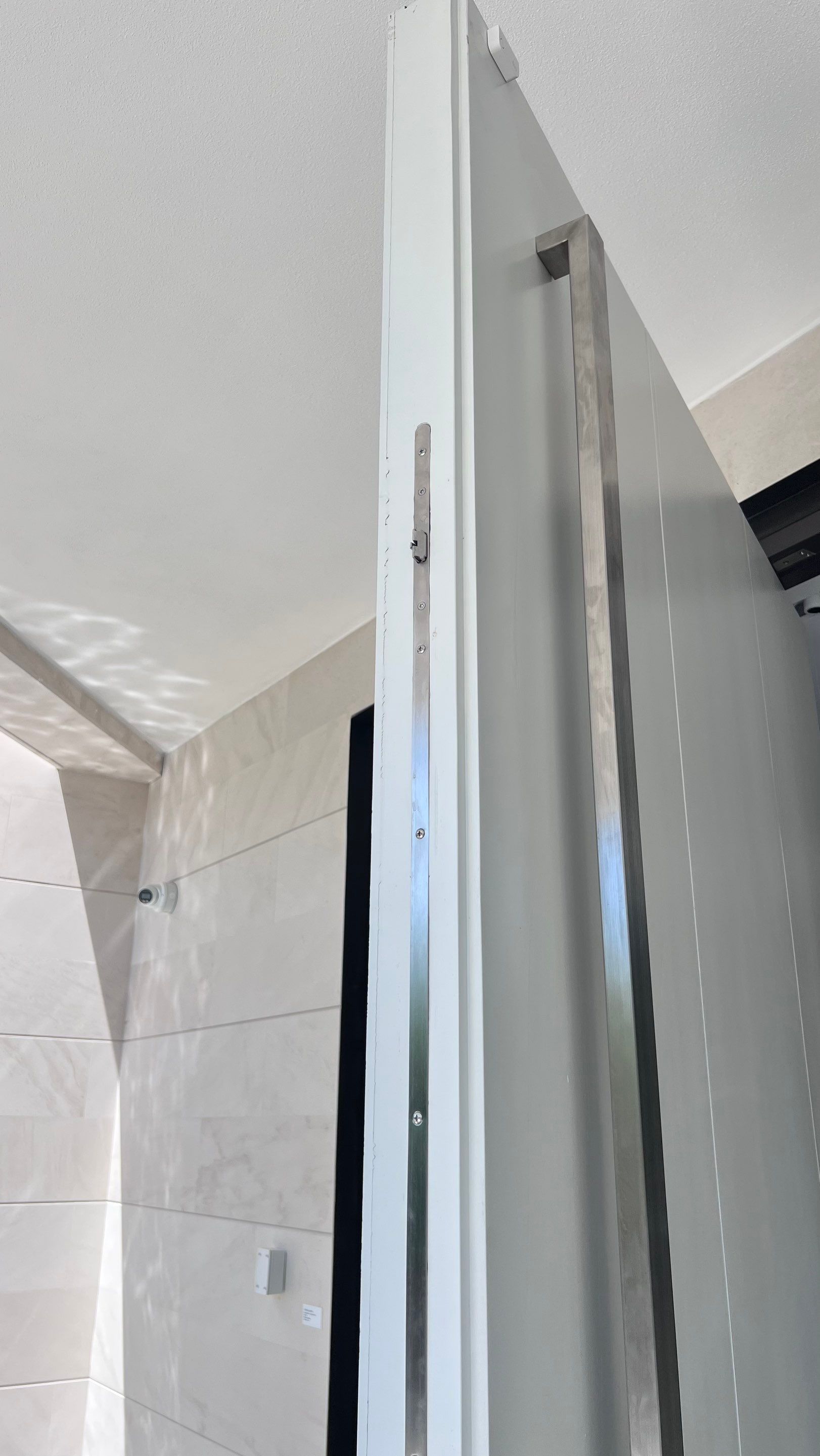 Custom Material Pivot Door installation by Impact Precious Wood Inc.